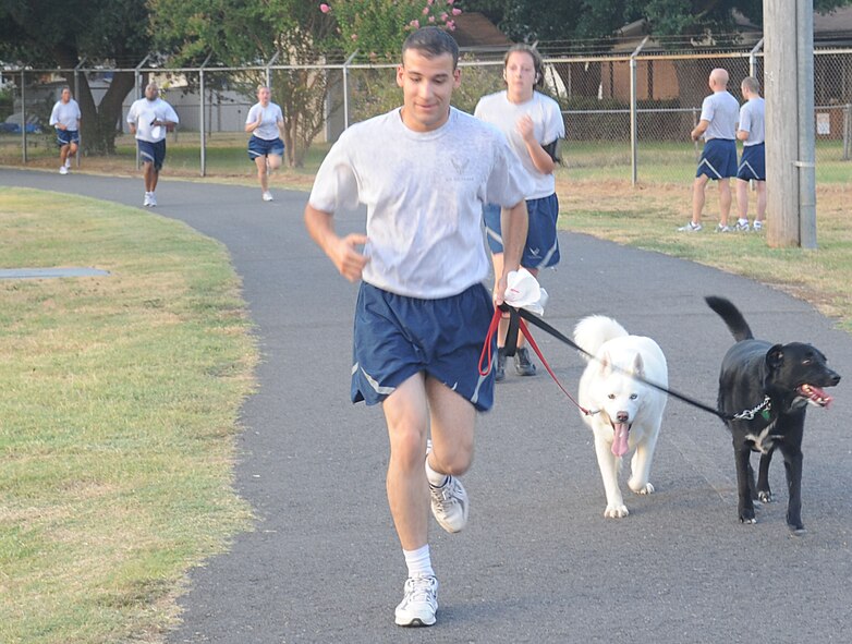 Airman 1st Class Diego Herrera-Mauri, 2nd Civil Engineer Squadron, runs  the "Back to School" fun run with his dogs, Kiba and Villa, on Barksdale Air Force Base, La., Aug. 18. A fun run is held once a month to help bring the base community together and promote physical fitness and the various programs the gym provides. (U.S. Air Force photo/Senior Airman Kristin High)(RELEASED) 