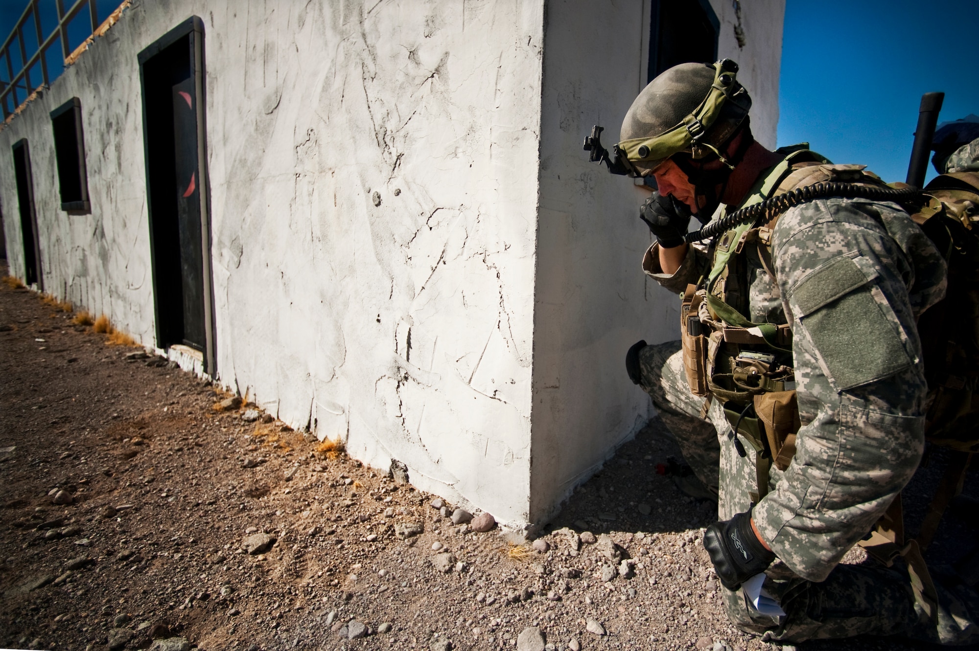 U.S. Air Force Tech. Sgt. Donald Urqhart, 5th Air Support Operations Squadron joint terminal attack controller, from Fort Lewis, Wash., takes cover behind a building while calling for a simulated air strike on a high value target during a Green Flag-West 11-9 training exercise Aug. 14, 2011, in the National Training Center at Fort Irwin, Calif. JTAC Airmen train with the 12th Combat Training Squadron as part of Green Flag-West to stay proficient and prepare for upcoming deployments. (U.S. Air Force photo by Tech. Sgt. Michael R. Holzworth/Released)

