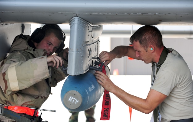 U.S. Air Force Tech. Sgt. Jason Hough and Airman 1st Class Trenton Metyk, 23rd Aircraft Maintenance Squadron weapons armament systems specialists, secure munitions onto an A-10C Thunderbolt II during a phase II operational readiness exercise at Moody Air Force Base, Ga., Aug. 17, 2011. An exercise evaluation team member evaluated Hough and Metyk on the proper procedures and efficiency in loading munitions onto the aircraft. (U.S. Air Force photo by Senior Airman Stephanie Mancha/Released)