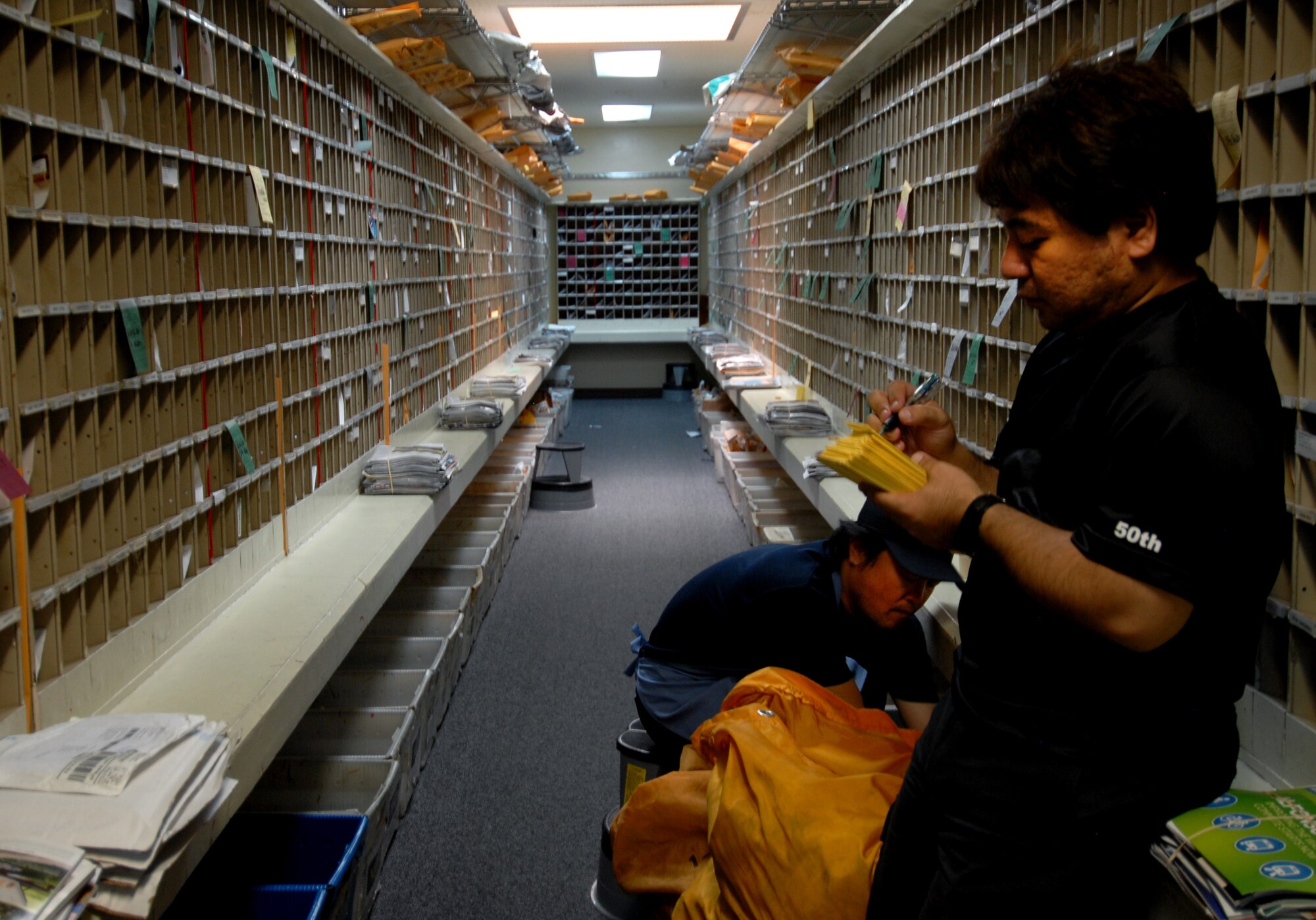 Yutaka Takaesu and Hiromichi Ginama, postal specialists at Kadena Air Base's Post Office, write package notices for post office patrons Aug. 17 at Kadena Air Base, Japan. Members of the Kadena post office have been working around the clock since Typhoon Muifa delayed thousands of pieces of mail from getting to the base. They have processed more than 3,805 pieces of Express, Letter-Class, Priority and Space Available mail totaling 83,829.5 lbs since the 60-hour typhoon. "The active duty Airmen and local nationals of the post office strive to process and deliver mail to Team Kadena within 24 hours of receiving mail trucks," said Wong. "The post office receives two to three trucks of mail on a daily basis." (U.S. Air Force photo/Senior Airman Sara Csurilla)