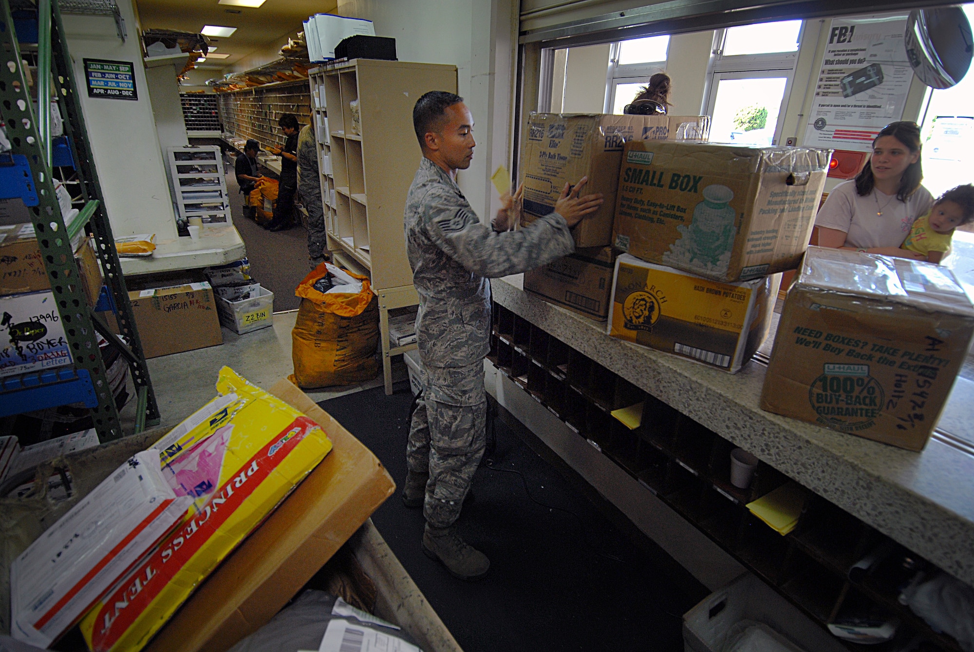 Staff Sgt. James Wong, a postal specialist with the 18th Communications Squadron, gives post office patrons their long awaited mail at the post office Aug. 17 at Kadena Air Base, Japan. Members of the Kadena post office have been working around the clock since Typhoon Muifa delayed thousands of pieces of mail from getting to the base. They have processed more than 3,805 pieces of Express, Letter-Class, Priority and Space Available mail totaling 83,829.5 lbs since the 60-hour typhoon. "The active duty Airmen and local nationals of the post office strive to process and deliver mail to Team Kadena within 24 hours of receiving mail trucks," said Wong. "The post office receives two to three trucks of mail on a daily basis." (U.S. Air Force photo/Senior Airman Sara Csurilla)