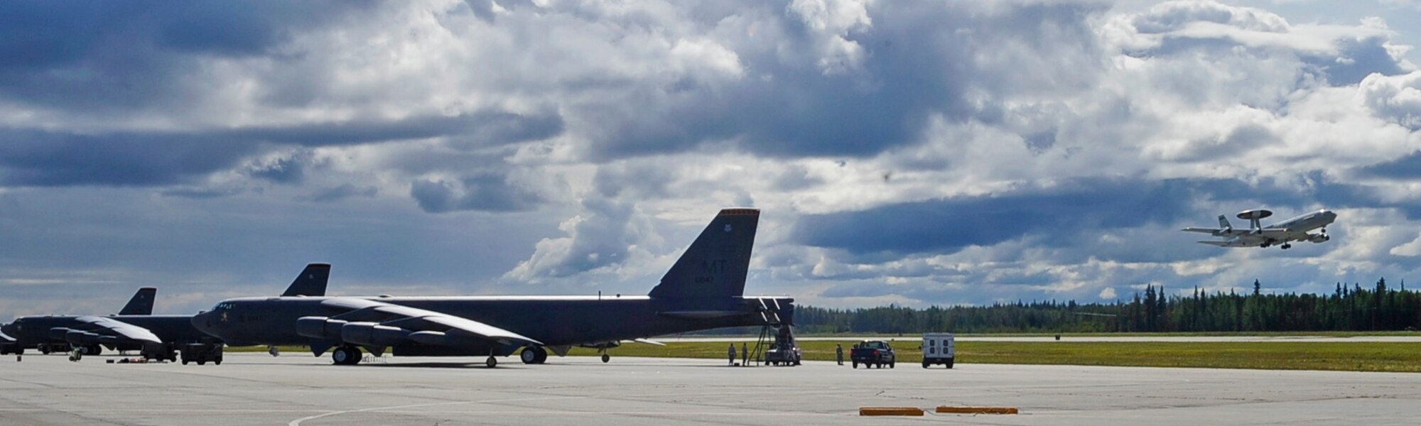 Three B-52H Stratofortress sit on the runway as an E-3 Sentry launches during RED FLAG-Alaska 11-3 August 15, 2011, Eielson Air Force Base, Alaska.  RF-A allows participating units to exchange tactics, techniques and procedures as well as improve interoperability.  The B-52s are assigned to the 69th Bomb Squadron, Minot Air Force Base, North Dakota. The E-3 Sentry is assigned to the 962nd Airborne Air Control Squadron, Joint Base Elmendorf-Richardson, Alaska. (U.S. Air Force photo/Staff Sgt. Miguel Lara III)

