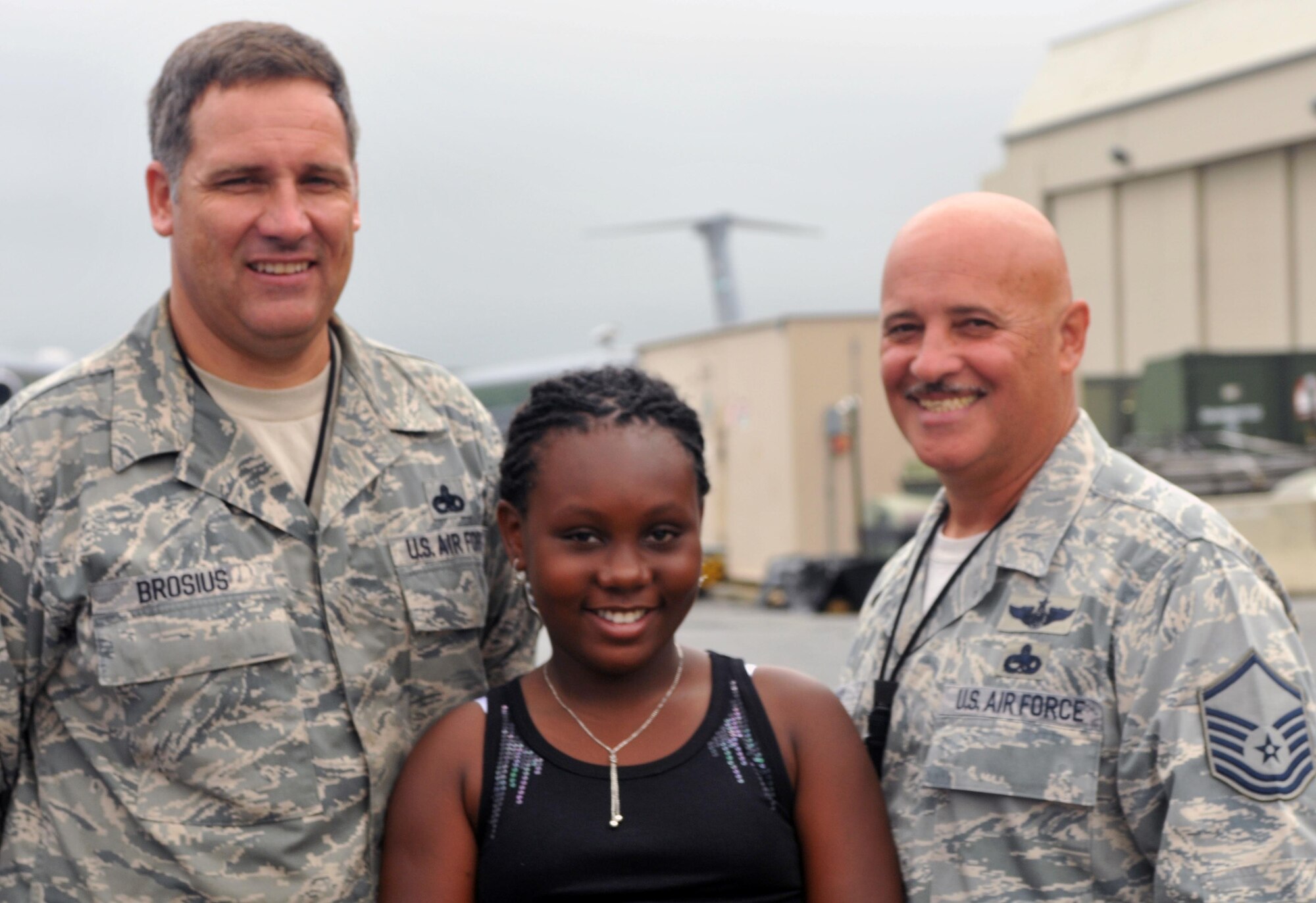 Jedvarline Baptiste, 10, shares a moment with Master Sgts. Curtis Brosius (left) and Richard Biasi, from the 512th Aircraft Maintenance Squadron, following a C-5 tour Aug. 15, 2011, on Dover Air Force Base, Del. As part of a program called Fresh Air Fund, the French-speaking girl, from Brooklyn, N.Y., lived with the family of Pam Jackson, 512th Financial Management Office chief. Jackson's daughter, Meaghan Ellwanger, made it possible for Jedvarline to experience several outdoor activities such as hiking and swimming as well as some indoor past times including crafting and scrapbooking. (U.S. Air Force photo by Sarah Starkey)