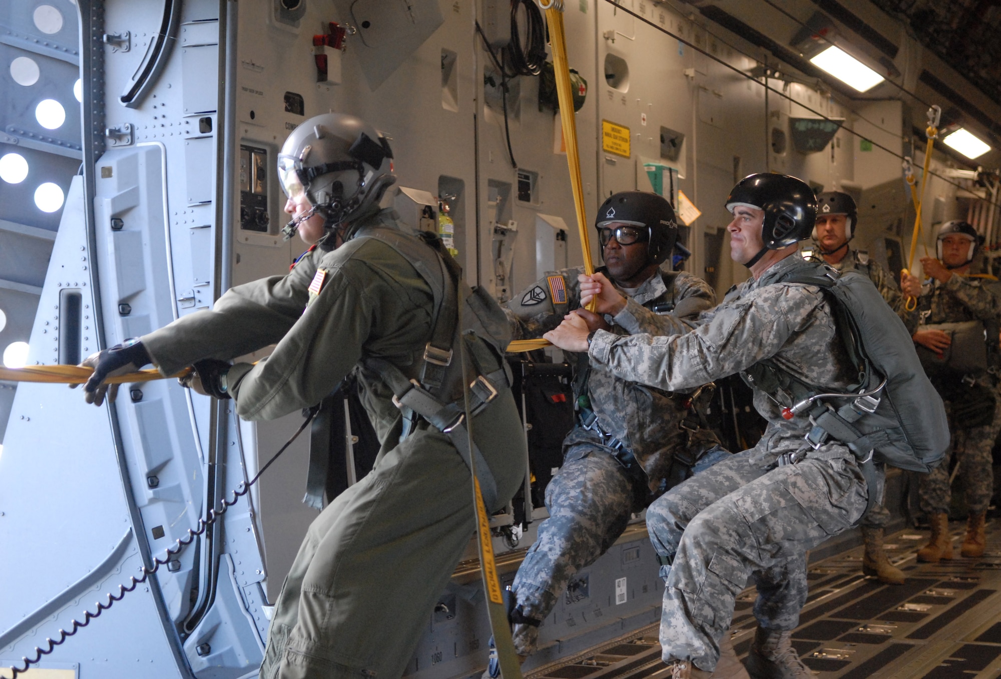 U.S. Air Force Senior Master Sgt. Chuck Baker, left, and members of the Special Operations Command, Pacific, drag a used parachute into a 535th Airlift Squadron C-17 over Hawaii skies Aug. 11. Baker is a loadmaster from Joint Base Pearl Harbor-Hickam, and the SOCPAC Soldiers flying with the 535th AS are from Camp Smith, Hawaii. They were performing static and HALO (high altitude-low opening) jumps to maintain proficiency and currency. (U.S. Air Force photo/Staff Sgt. Carolyn Herrick)