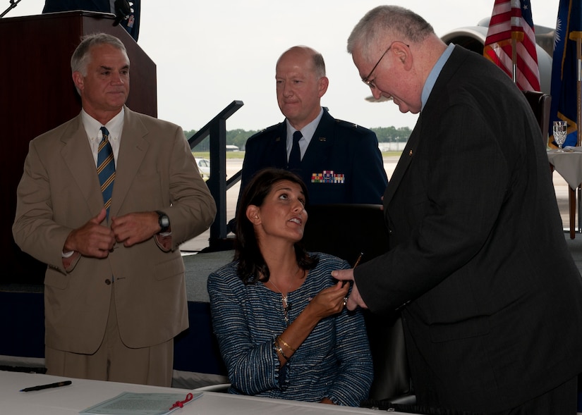South Carolina Governor Nikki Haley presents retired Navy Rear Adm.James Carey one of the pens she used to sign the Overseas Citizens Absentee Voters Act  at Joint Base Charleston Aug. 17. Also pictured are South Carolina Senator Chip Campsen and Brig. Gen. Grady Patterson. Patterson is the assistant adjutant general for South Carolina National Guard and Carey is the senior policy advisor to the Pew Center on the states.  (U.S. Air Force photo/Staff Sgt. Katie Gieratz)