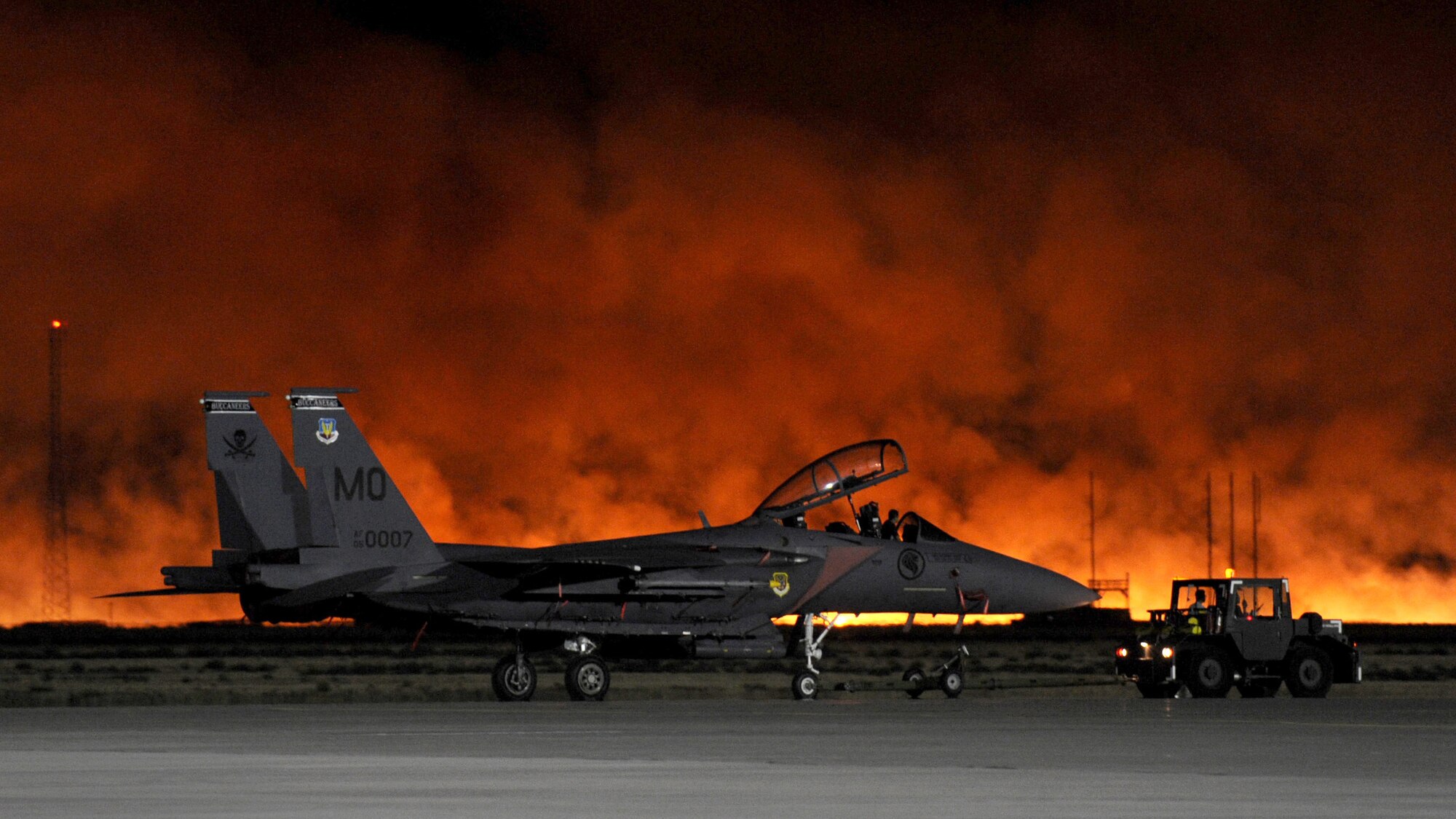 A brush fire lights up the evening sky behind an F-15SG at Mountain Home Air Force Base, Idaho, Aug. 15, 2011. Flightline activity was stopped and personnel were evacuated from flightline buildings as the fire approached the base. The fire burned approximately 3,000 acres, including five acres on the northwest corner of the base. (U.S. Air Force photo/Staff Sgt. Gina Chiaverotti-Paige)