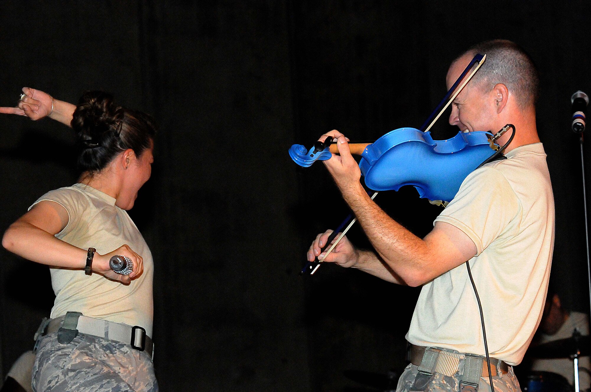 BAGRAM AIRFIELD, Afghanistan – Staff Sgt. Angie Johnson(left) Air Forces Central Public Affairs band “Sidewinder” vocalist and Capt. John Arata fiddler (right) perform at the flag pole in Camp Cunningham Bagram Afghanistan, Aug. 14.  The band played multiple shows each day to allow as many people as possible to attend the events. (U.S. Air Force photo/ Senior Airman Krista Rose) 