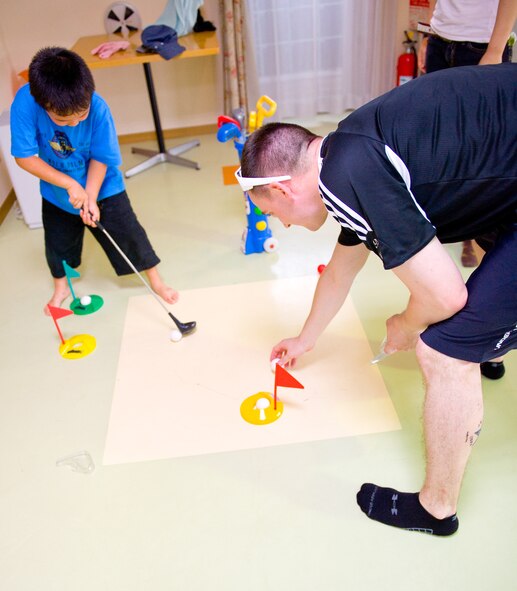 TACHIKAWA, Japan -- An Airman from the 374th Security Forces Squadron sets up a miniature golf game for a child at the Shisei Gakusha children's home in Tachikawa, Japan, Aug. 16, 2011. 374th SFS Airmen from Yokota Air Base, Japan, donated toys, clothing and food for the children, in an act of good will towards their off-base neighbors. (U.S. Air Force photo/Airman 1st Class Krystal M. Garrett)