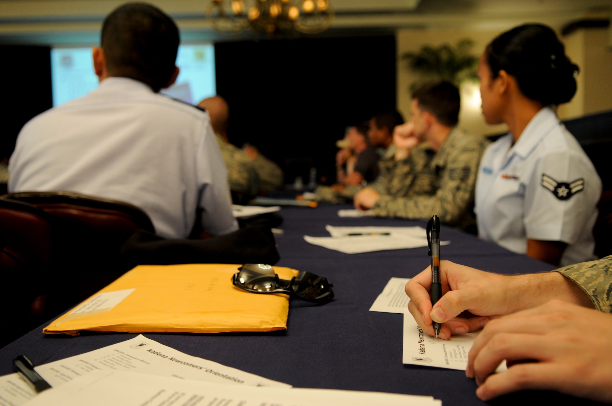 People attending the Airman and Family Readiness Center’s newcomers orientation briefing listen, and some take notes, while a speaker addresses the audience on different aspects of Kadena and Okinawa at the Kadena Officers’ Club Aug. 17. Though participating in an Operational Readiness Inspection, Kadena personnel are still working to ensure even the typical every day duties are completed. (U.S. Air Force photo/Airman 1st Class Maeson L. Elleman)