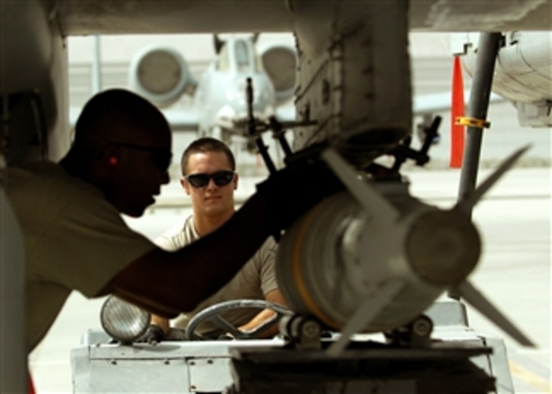 U.S. Air Force Staff Sgt. Robert Corso steadies the MJ-1B Jammer delivering a GBU-38 bomb to an A-10C Thunderbolt II while Staff Sgt. Renaldo Richardson (left) guides it into place on Kandahar Airfield, Afghanistan, on Aug. 8, 2011.  