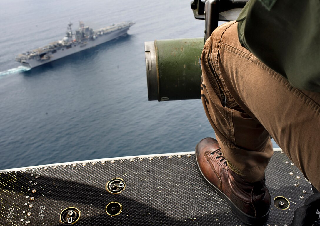 The amphibious assault ship Makin Island sails off Southern California’s coast during a training mission Aug. 18 in which Navy and Marine Corps helicopters provided observation. Makin Island and USS New Orleans simulated transiting a natural passageway connecting two large bodies of water. Pictured in the foreground is helicopter crew chief Lance Cpl. Michael H. Dionne, flying in a UH-1Y Huey Venom. Dionne, 21, hails from Mayslanding, N.J., and serves with Marine Medium Helicopter Squadron 268 (Reinforced), the aviation combat element of the 11th Marine Expeditionary Unit, embarked on the ships and scheduled to deploy this fall.