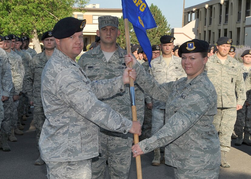 Lt. Col. Jason Beers, 377th Security Forces Group commander, hands the guidon to 1st Lt. Heather Chaale, 377th Security Forces Squadron commander, during Monday’s reactivation of the 377 SFG. (photo by Todd Berenger)