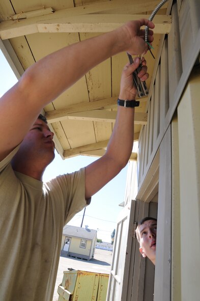 Senior Airman Eric Hartman (left) and Senior Airman Philip Gray, power production specialists with the 126th Civil Engineering Squadron, Illinois Air National Guard, wire up a replacement exterior light during a building renovation at Camp Roberts, Calif. The Army National Guard training base was created in 1941 to support troops leaving for World War II and is now in need of repairs to buildings and infrastructure. Air National Guard Civil Engineering squadrons, known as "Prime Beef" units when deployed, are using the opportunity to train on real world electrical, structural, plumbing and heavy equipment scenarios. This creates a  collaboration that proves valuable to both National Guard components.