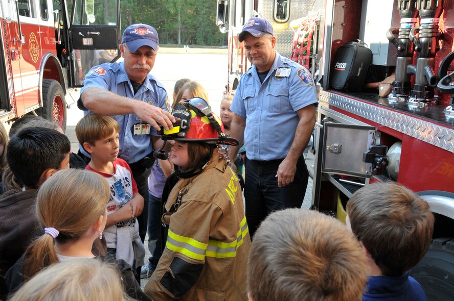 From left, Charlie Armstrong, AEDC Fire Department firefighter crew chief, and Jay Baldwin, a driver operator with the department, interact with a third grade class touring the fire department as part of a Spark program visit to the base. (Photo by Rick Goodfriend)  