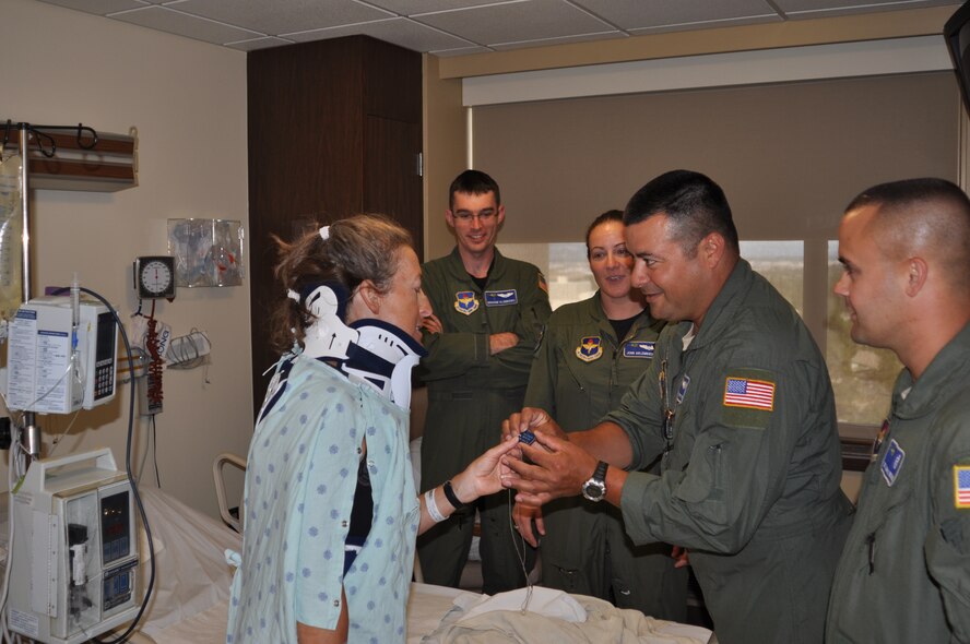 Tech. Sgt. Steven Perez, 36th Rescue Flight, presents Paulette Kirby, with their unit dog tag at Sacred Heart Medical Center in Spokane, Wash., Aug 17. The day before, the four-man helicopter crew pictured from left to right (Capt. John Alsbrooks, Capt. Jennifer Golembiewski, Perez and Tech. Sgt. Joseph Brownell) had rescued Kirby Thompson Pass, Idaho following a bicycle accident. This is the 36th RQF’s 663rd rescue. (U.S. Air Force photo/Scott King)
