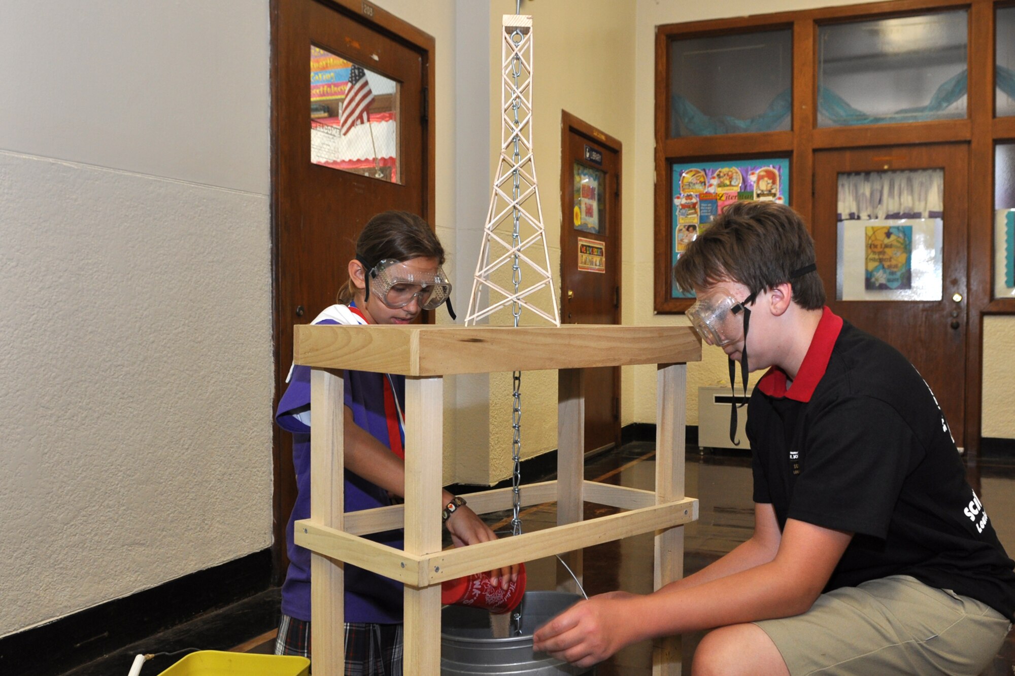 Marie Marcalus pours sand into a bucket suspended from a chain resting on top of a tower constructed of balsawood and super glue while Alan Hedrick keeps the bucket from moving during a demonstration, Aug. 17, 2011. “Towers” is an exercise where towers constructed by students are put to a weight test where a bucket is attached to the top of the tower on a chain and filled with sand to evaluate the strength of the construction and design, and how much weight it takes to collapse the tower.  Marie and Alan are students at St. John Berchmans Catholic School in Shreveport, La., and participated in the STARBASE Louisiana program at Barksdale Air Force Base, La., when they were 5th Graders.  The STARBASE program, which is supported by the 307th Bomb Wing, presents an exciting 25-hour hands on/minds on aviation and aerospace curriculum to area 5th grade students and their teachers. The DoD program is committed to addressing the critical needs in STEM education - Science, Technology, Engineering and Mathematics. STARBASE Louisiana introduces its students to exciting STEM education topics, inspiring these young minds to further explore these topics in future course work. (Courtesy photo by Jeff Walston)