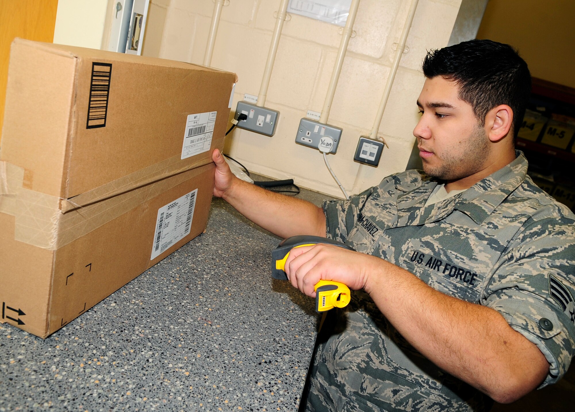 RAF MILDENHALL, England – Senior Airman Nolan Luna-Chavez, 100th Communications Squadron postal clerk, scans a parcel before handing it to a customer here Aug. 19, 2011. The parcels are scanned to track the packages that have been received by customers and to allow for confirmation to be given to the sender. (U.S. Air Force photo/Senior Airman Ethan Morgan)