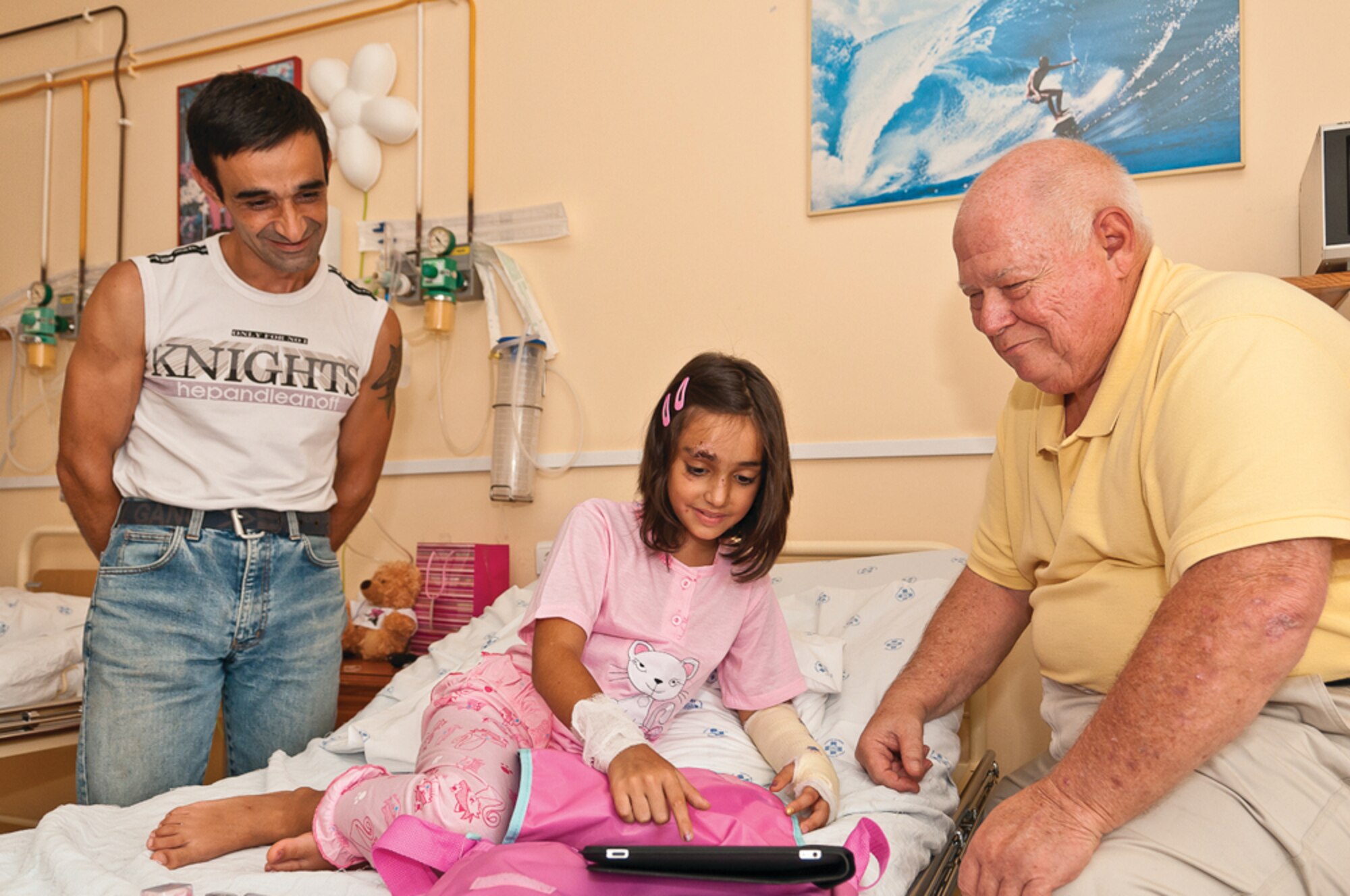 (Far right) Thomas McKendrick, 65th Medical Support Squadron, visits 8-year-old Marta Raposo in Angra hospital Aug. 16 while Marta's father, Eduino Raposo, looks on.  Mr. McKendrick saved Marta from an untimely death after she fell about 20 feet off a platform of the pool onto large rocks below, hitting her head. (Photo by Lucas Silva) 