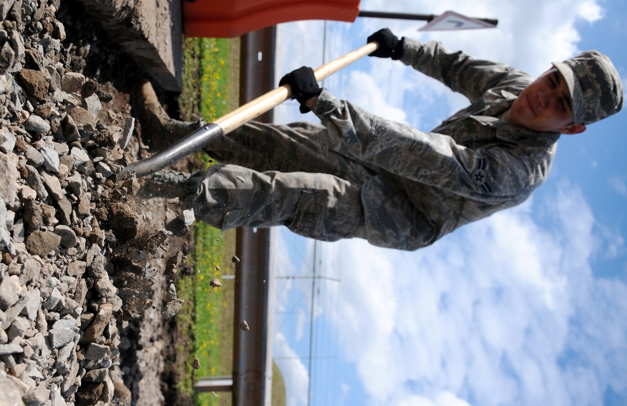 SPANGDAHLEM AIR BASE, Germany – Airman 1st Class Zachary Costa, 52nd Civil Engineer Squadron pavement and equipment apprentice, shovels dirt and rocks to clear a road in preparation for road repairs here Aug 16. Pavement and equipment Airmen are combat engineers who train continuously to perform a variety of maintenance projects. The projects, which include airfield sweeping, road maintenance and snow removal, ensure Sabers and their families can drive safely on base. (U.S. Air Force photo/Senior Airman Nick Wilson)

