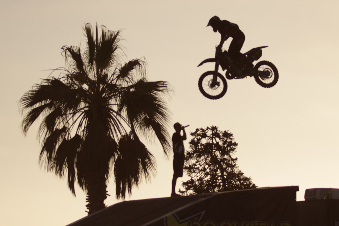 A motocross stuntman clears a jump over an announcer during Camp Pendleton’s first Endless Summer Night event at the San Onofre Beach, Aug. 19. Bon Jovi’s lead guitarist, Richie Sambora, visited the event to give out his personally designed and autographed guitars and also played his hit songs on stage.