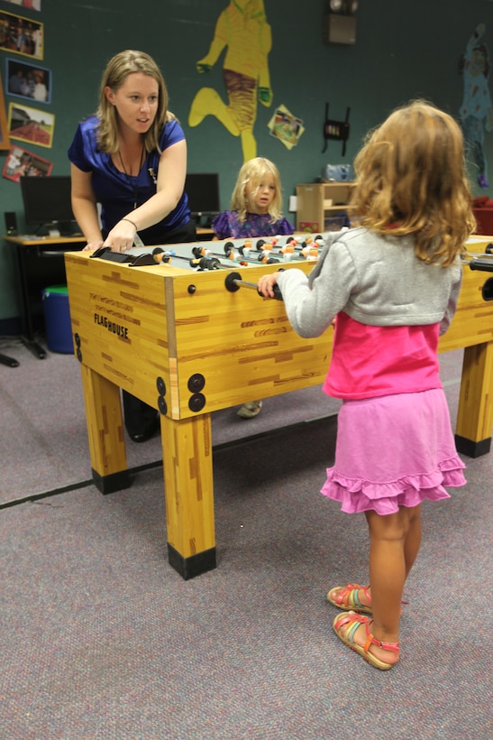 Jennifer Triolo, School Age Care program assistant leader, teaches future School Age Care Program attendants how to play foosball during the Stone Street Pavilion open house, Aug. 20. School Age Care is offered to students kindergarten through 12 years old from 5:45 to 8 a.m. and from the 2:30 to 6 p.m. at both the Stone Street and Tarawa Terrace Youth Pavilions and provides bus service to and from school.