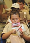 Zachary Southerland, son of Lt. Col. Michael Sutherland, Joint Electronic Warfare Center, delves into a Meal-Ready-to-Eat. (U.S. Air Force photo/Robbin Cresswell)