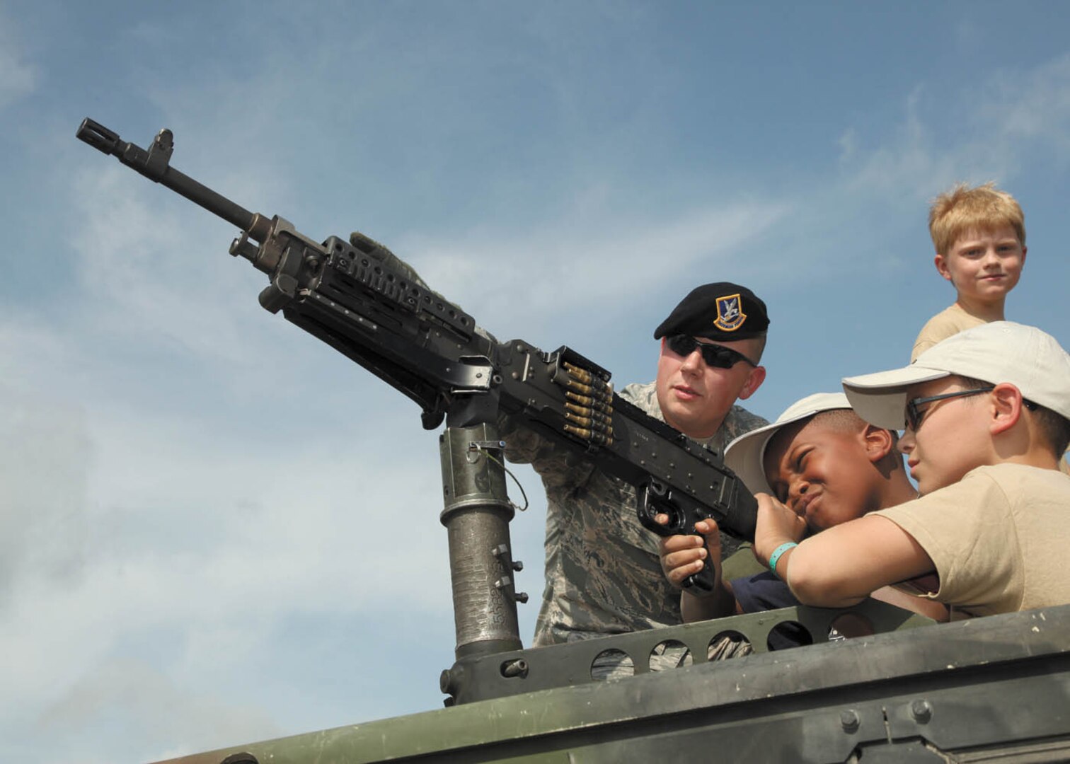 Tech Sgt. Douglas Reed, heavy weapons instructor with the 343rd Training Squadron, allows Zane Oden, son of retired Navy seaman Stanley Oden, and Nathaniel Schaffer, son of Tech. Sgt. Tiffany Schaffer, to take hold of the M240 machine gun. (U.S. Air Force photo/Robbin Cresswell)