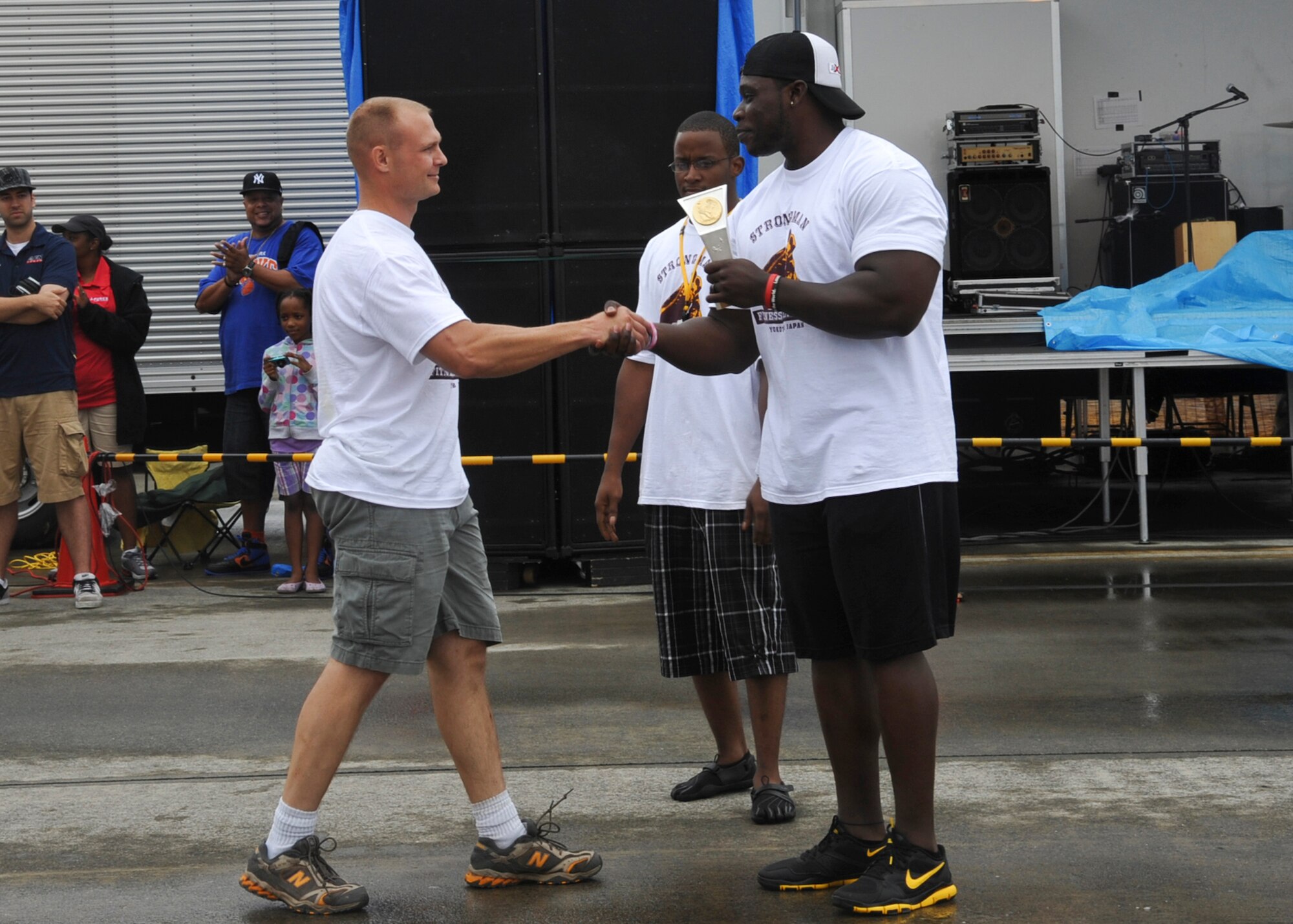 YOKOTA AIR BASE, Japan -- Mario Gifford (right), a personal trainer, awards a trophy to U.S. Marine Corps Capt. Eric Corbett, U.S. Forces, Japan, for winning first place in the 2011 Strongman Competition at Yokota Air Base, Japan, Aug. 21, 2011. This was Captain Corbett's first time participating in the competition, held each year during Yokota's Friendship Festival. (U.S. Air Force photo/Senior Airman Andrea Salazar) 