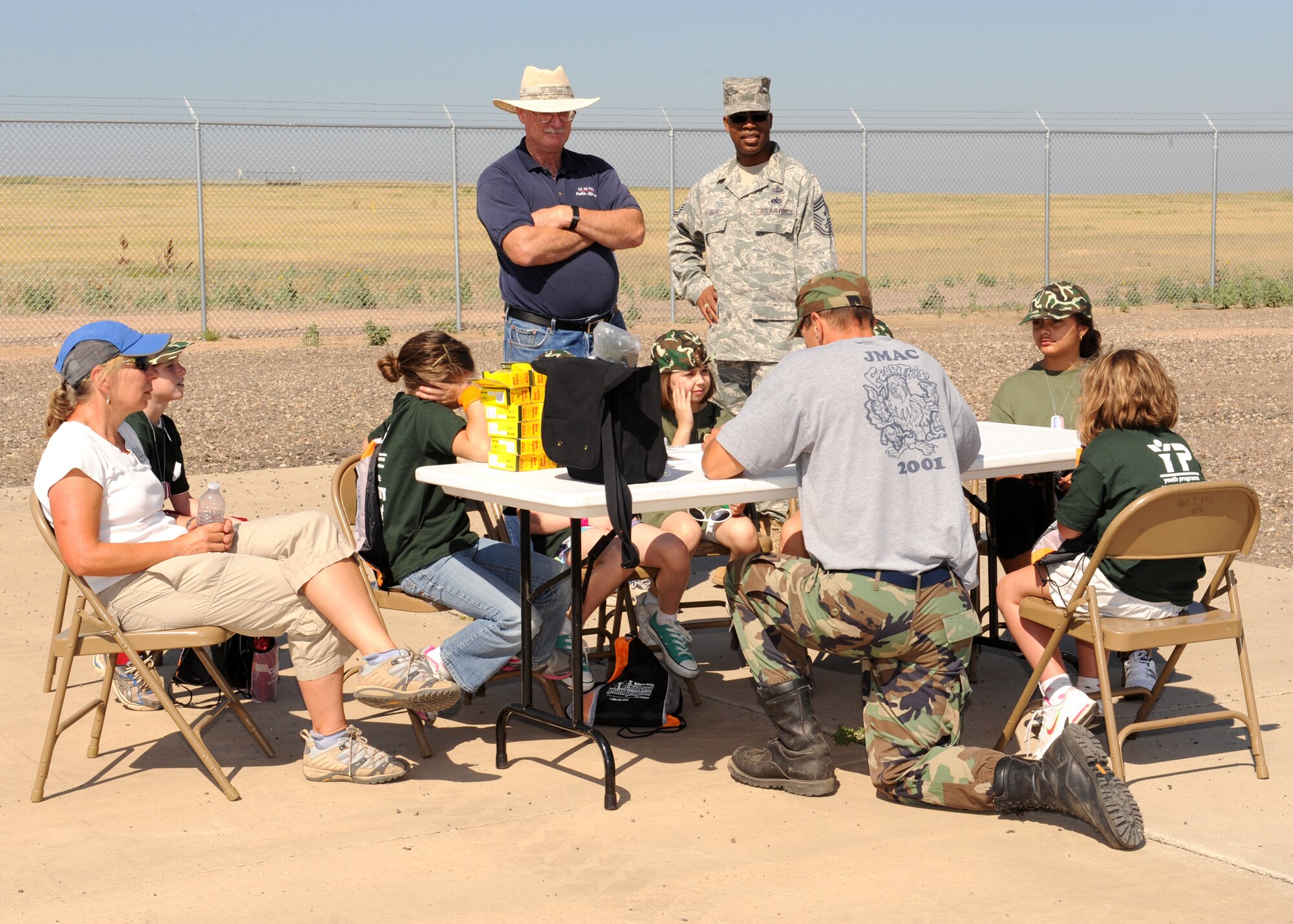 BUCKLEY AIR FORCE BASE, Colo. -- Mr. John Spann, 460th Space Wing Public Affairs director, Command Chief Master Sgt. Robert Ellis, 460th Space Wing, and Mr. Thomas Cox, 460th Force Support Squadron, instruct a group of children how to be public affairs journalists and photographers Aug. 13 2011. (U.S. Air Force photo by Senior Airman Marcy Glass)
