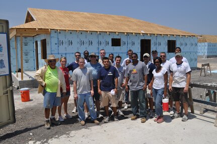 Eighteen of 25 volunteers from the 67th Network Warfare Wing pose for a group shot at the Habitat for Humanity-San Antonio build site Aug. 11. The team battled against sweltering heat and bees sharing the drinking water to build the first layer of the roof. More than 12,000 people volunteer at the site each year. (U.S. Air Force photo by Tech. Sgt Scott McNabb)
