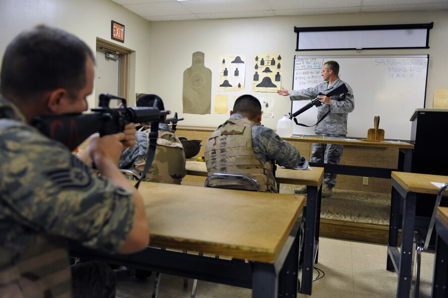 Senior Airman Nicholas Niles, Combat Arms Training and Maintenance instructor, tells Airmen to aim at a target during the CATM course on Barksdale Air Force Base, La., Aug. 18. The Airmen qualified with the M-16A2 rifle while wearing a helmet and interceptor ballistics armor. Airmen in the course also donned gas masks to help them get use to aiming the weapon in a contaminated environment. (U.S. Air Force photo/Airman 1st Class Micaiah Anthony)(RELEASED)