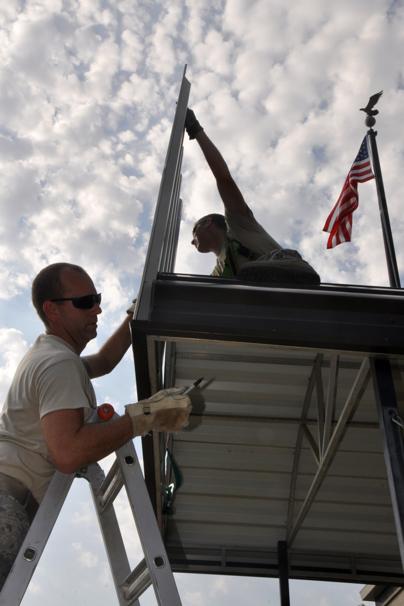 Senior Airman Brad Morgan, a knowledge operations management journeyman, holds a piece of metal steady as Tech. Sgt. Christopher Collins, an electric power production technician prepares to mark it for cutting, so it can be secured to an awning structure at the 307th Bomb Wing Headquarters building at Barksdale Air Force Base, La., Aug. 18, 2011. Both Airmen are assigned to the 307th Civil Engineer Squadron at Barksdale AFB. Routine maintenance and repairs at the 307th BW are now accomplished by the Airmen of the 307th CES. Letting Traditional Reservists maintain their own buildings gives them the opportunity to take ownership and pride in their facilities, saving taxpayer dollars and allowing the Airmen to continue their skills training. Following an $18,000 bid to repair the main entrance awning at the 307th BW, a decision was made to allow 307th CES Airmen to replace the material awning with a more durable longer lasting metal one. After the cost of materials and labor, the projected savings to American taxpayers is approximately $16,000. (U.S. Air Force photo/Tech. Sgt. Jeff Walston)