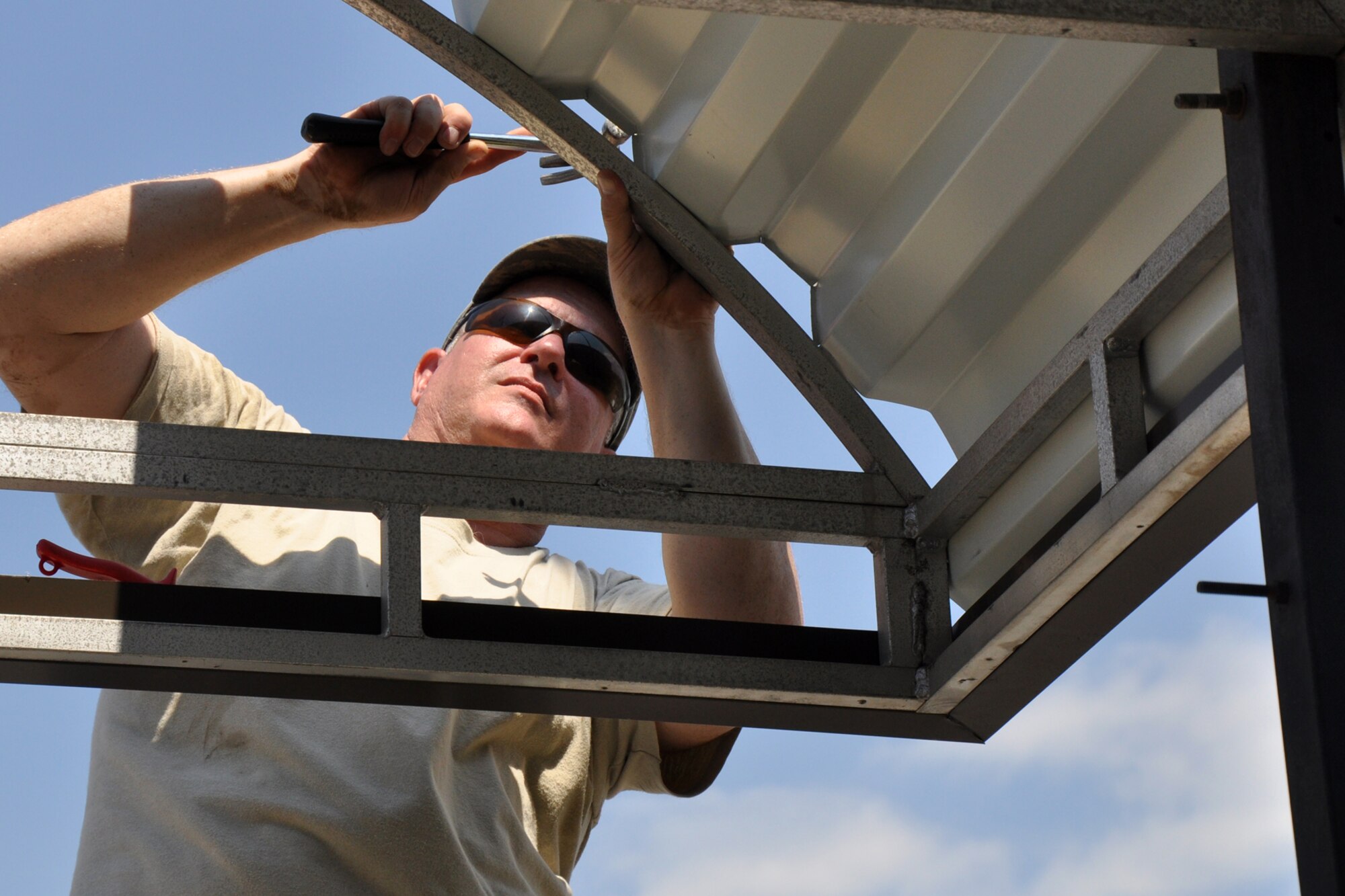 Tech. Sgt. Roy Stockinger, a structural carpenter assigned to the 307th Civil Engineer Squadron, taps a sheet of metal into place on an awning structure at the 307th Bomb Wing Headquarters building at Barksdale Air Force Base, La., Aug. 15, 2011. Routine maintenance and repairs at the 307th BW are now accomplished by the Airmen of the 307th CES. Letting Traditional Reservists maintain their own buildings gives them the opportunity to take ownership and pride in their facilities, saving taxpayer dollars and allowing the Airmen to continue their skills training. Following an $18,000 bid to repair the main entrance awning at the 307th BW, a decision was made to allow 307th CES Airmen to replace the material awning with a more durable and longer lasting metal one. After the cost of materials and labor, the projected savings to American taxpayers is approximately $16,000. (U.S. Air Force photo/Tech. Sgt. Jeff Walston)