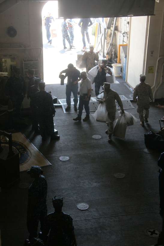 Marines and Sailors aboard amphibious transport dock USS Mesa Verde (LPD 19), bring civilian contractors and mail aboard the ship while in port at Naval Air Station Sigonella, Italy, Aug. 22, 2011. The Marines and sailors of the 22nd Marine Expeditionary Unit are currently deployed with Amphibious Squadron 6 (PHIBRON 6) aboard the USS Bataan Amphibious Ready Group (BATARG) and will continue to train and improve the MEU’s ability to operate as a cohesive and effective Marine Air Ground Task Force.  The 22nd MEU is a multi-mission, capable force, comprised of an Aviation Combat Element, Marine Medium Tilt Rotor Squadron 263 (Reinforced)(VMM-263 (REIN)); a Logistics Combat Element, Combat Logistics Battalion 22(CLB 22); a Ground Combat Element, Battalion Landing Team, 2nd Battalion, 2nd Marine Regiment(BLT 2/2) and its Command Element.