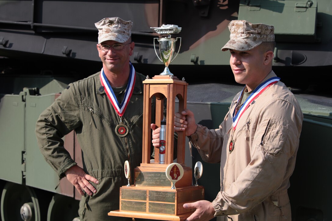 Gunnery Sgt. Darrell R. Penyak (left) and Cpl. Michael T. Angelo, tank crewman with Company D, 2nd Tank Battalion, 2nd Marine Division, pose with the Robert H. McCard Cup aboard Marine Corps Base Camp Lejeune, August 23. The Marines were part of the crew who won the award for the highest score during a Corps wide tank qualification competition in Boise, Idaho.
