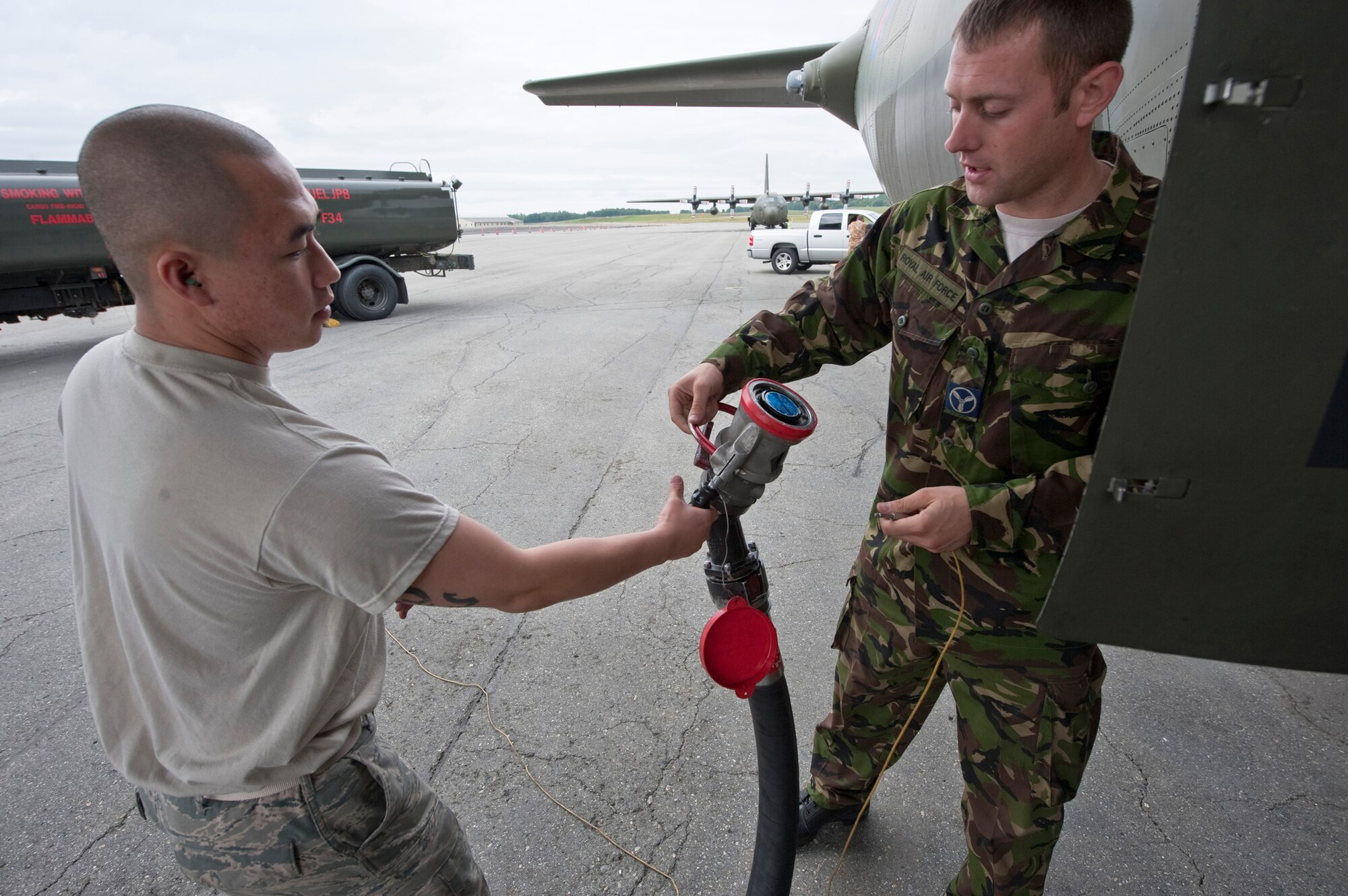 JOINT BASE ELMENDORF-RICHARDSON, Alaska -- Royal Air Force Senior Aircraftman John Morton, right, a member of the No. 47 Squadron from Brize Norton Station, United Kingdom, hands a fuel hose over to Airman 1st Class Tou Yang, a member of the 673d Logistics Readiness Group, during a refuel a U.K. C-130 Hercules during Red Flag-Alaska 11-3 Aug. 22. The 47th traveled from the U.K. with 56 members of the RAF to participate in RF-Alaska. While here they will work on enhancing their skills in cargo-air drops, electronic warfare, assault-strip landings and more. (U.S. Air Force photo/Senior Airman Christopher Gross)