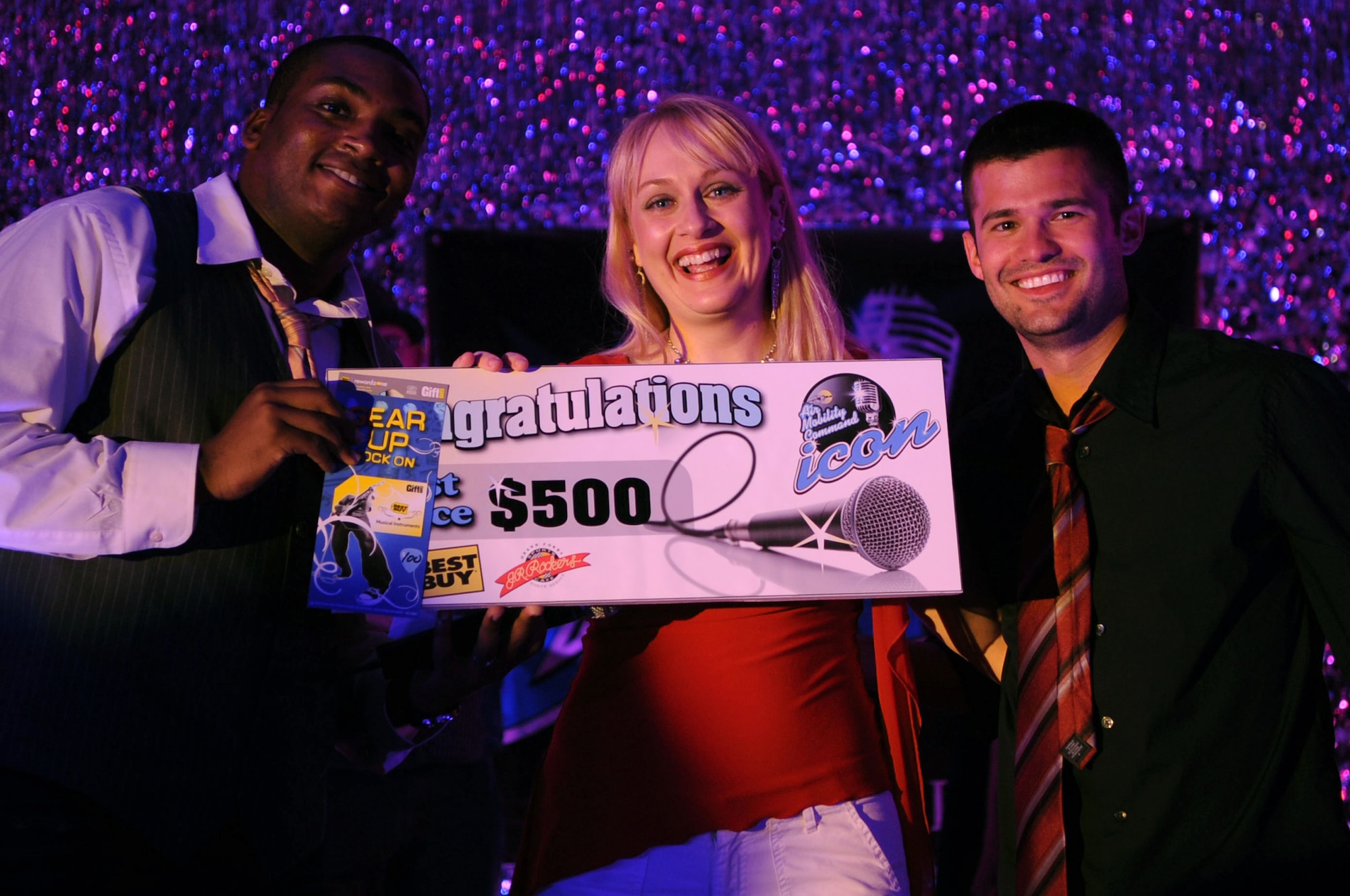 Katie Peavy, wife of Staff Sgt. Jeffery Peavy 319th Communications Squadron technician, receives her 1st place prize at the Air Mobility Command Icon Contest on Grand Forks Air Force Base Aug 18. AMC Icon’s contest is conducted annually and is a great way for GFAFB members to be center stage while highlighting their talents. Since Mrs. Peavy is not a member of the Air Force Senior Airman Josh Maness, from the 319th Logistics Readiness Squadron, will be representing GFAFB at AMC Headquarters, Scott AFB in October. (U.S. Air Force photo by Senior Airman Amanda N. Stencil)