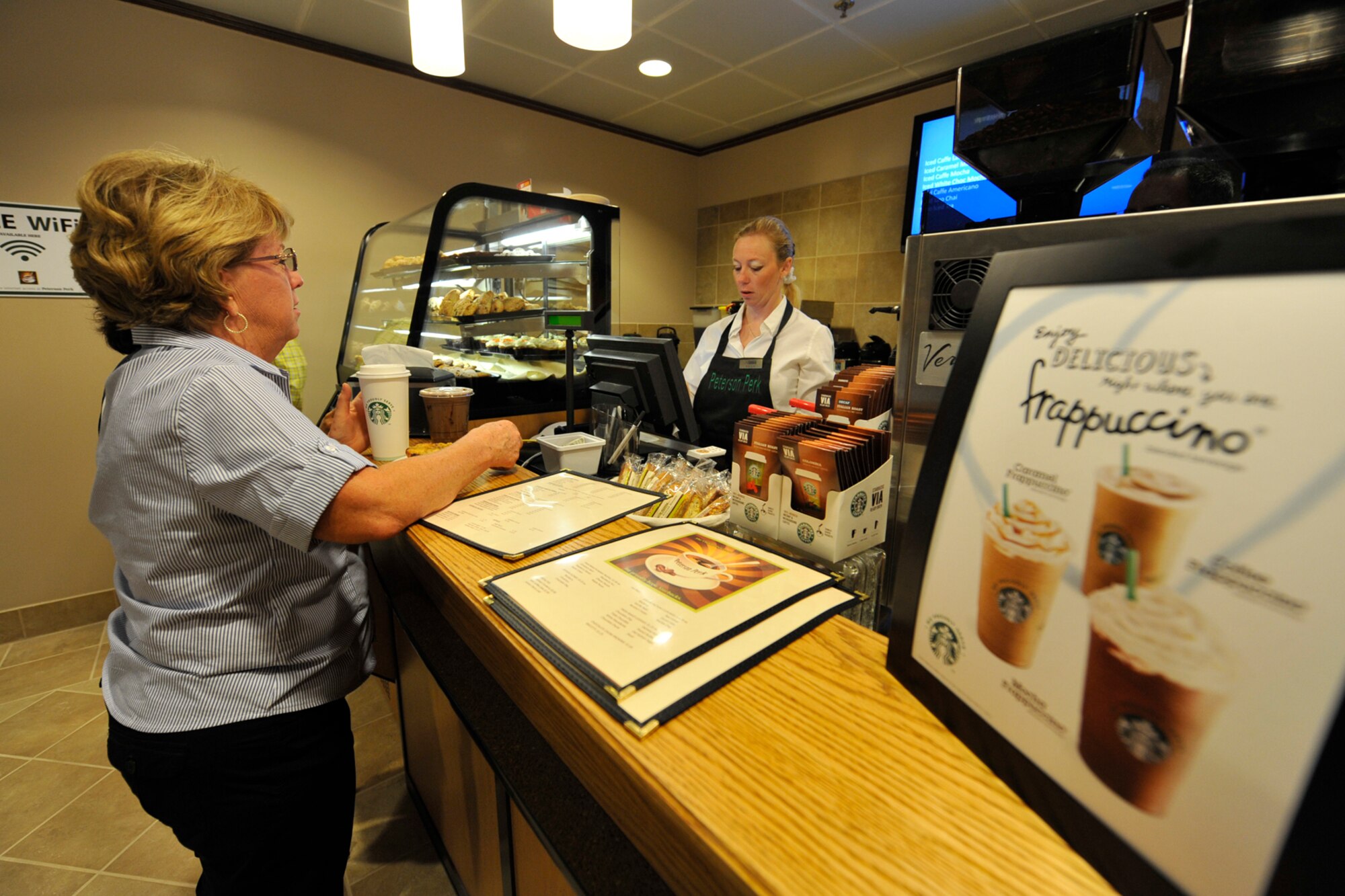 PETERSON AIR FORCE BASE, Colo. - Pat Stonerock (left), 21st Force Support Squadron accounting office, gets her hot cup of Joe from barista Paula Chekroun Aug. 19 at Peterson Perk. Located at The Club, the new coffeehouse is open 6 a.m.-2 p.m. Monday to Friday, offering a variety of snacks and caffeinated beverages. (U.S. Air Force photo/Rob Bussard)
