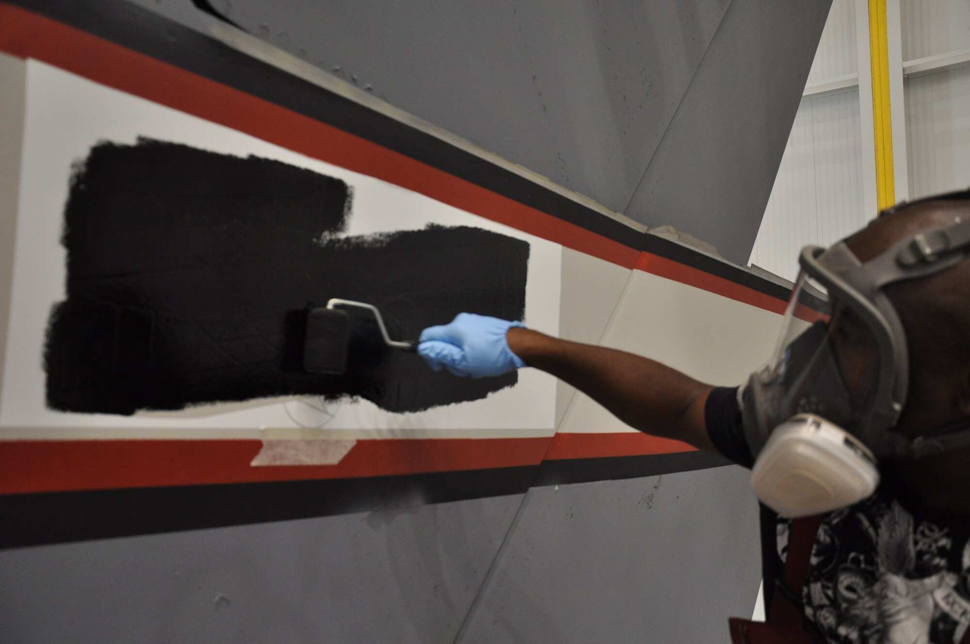 WRIGHT-PATTERSON AIR FORCE BASE, Ohio -Tech. Sgt. Aaron Bullucks, 445th Maintenance Squadron, uses a stencil to paint the Wright Flyer logo on a 445th Airlift Wing C-17 Globemaster III Aug. 18. (U.S. Ai Force photo/Staff Sgt. Amanda Duncan)