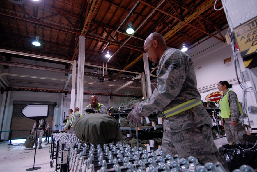 Staff Sgts. Stephen Head and Jimmy Fulleros, mobility baggage handlers assigned to the personnel deployment function at the 129th Rescue Wing, rolls out a  member's baggage to an awaiting pallet during an Operational Readiness Exercise at Moffett Federal Airfield, Calif., August 6, 2011.  (Air National Guard photo by Tech. Sgt. Ray Aquino)