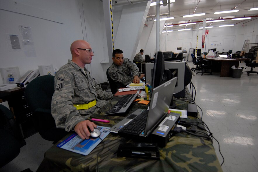 Senior Master Sgt. Tim Lewis and Master Sgt. Mark Vindiola, cargo deployment function personnel assigned with the 129th Logistics Readiness Squadron, prepare documents for outbound air freight cargo during an Operational Readiness Exercise at Moffett Federal Airfield, Calif., August 7, 2011.  (Air National Guard photo by Tech. Sgt. Ray Aquino)