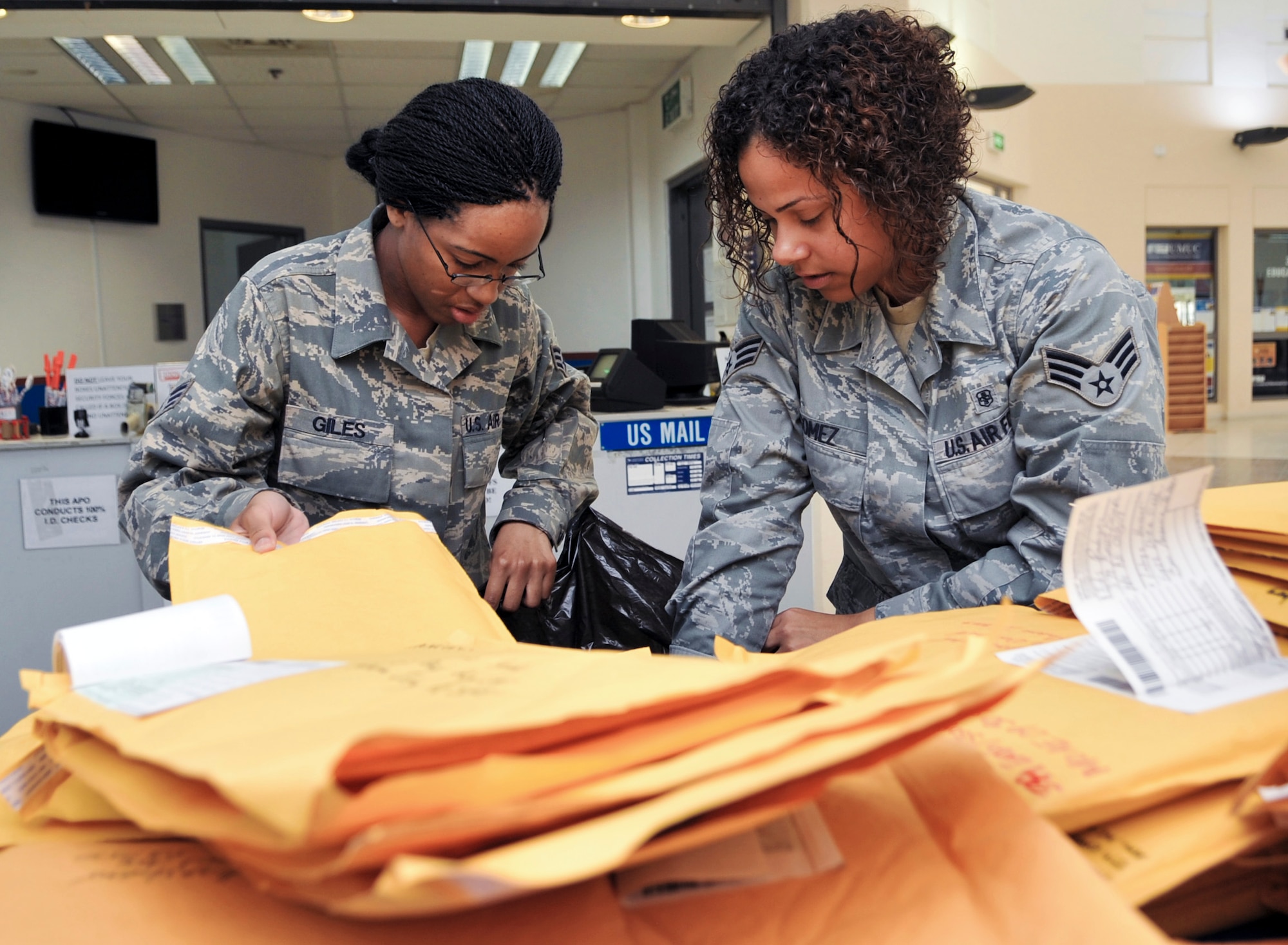 Senior Airmen Veronica Giles and Carolina Gomez, 379th Expeditionary Communications Squadron postal clerks, sort through mail and packages Aug. 18 at the post office. Giles,  a native of Raleigh, N.C., is deployed from Shaw Air Force Base, S.C.  Gomez, who hails from the Bronx, N.Y., is deployed from Spangdahlen Air Base, Germany. (U.S. Air Force photo/Senior Airman Paul Labbe)