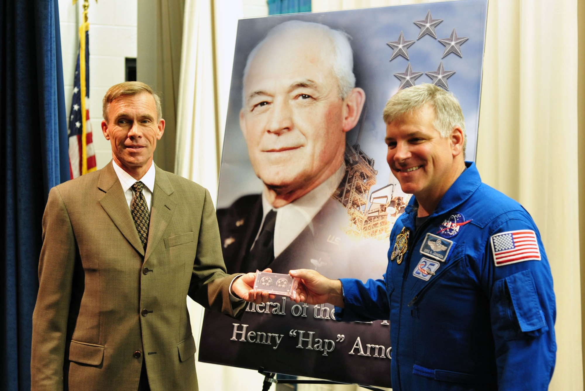 DAYTON, Ohio -- Astronaut Gregory H. Johnson (right) presents Museum Director Lt. Gen. (Ret.) John L. "Jack" Hudson (left) with a set of Gen. Hap Arnold's 5-star insignia, which was carried aboard the Space Shuttle Endeavour as it made its final voyage into space. During Family Day on Aug. 20, 2011, Johnson discussed his mission as pilot on Endeavour's last flight and returned the insignia to the museum. (U.S. Air Force photo by Jermont Chen)