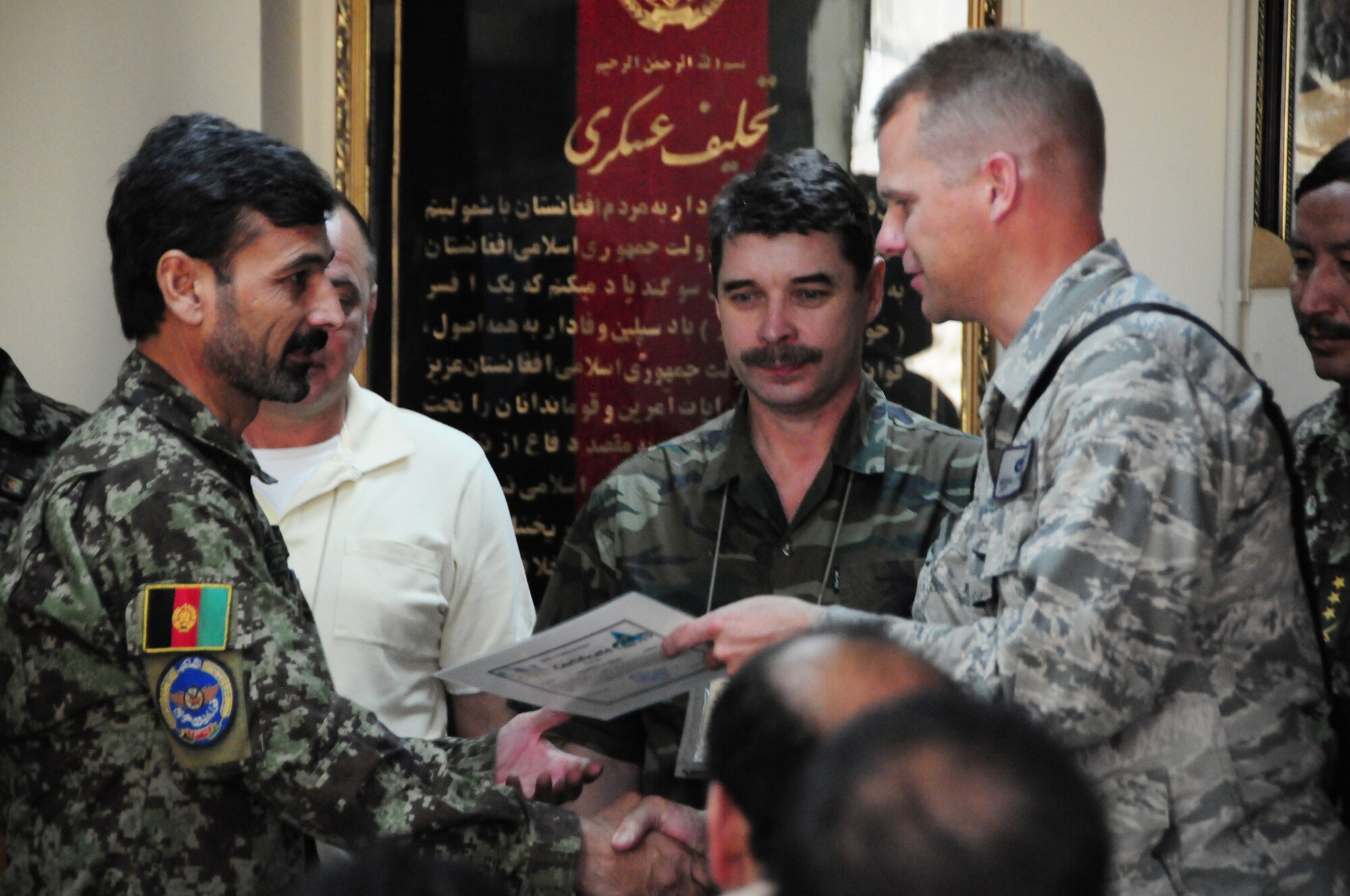 U.S. Air Force Capt. Michael Bradley, 438th Air Expeditionary Advisory Group, congratulates an Afghan Air Force airmen at Kabul International Airport, August 23, 2011.  Eleven graduates completed an Mi-17 intermediate level engine and body course which will allow them to become mid-level supervisors.  (U.S. Air Force photo by Senior Airman Amber Williams)