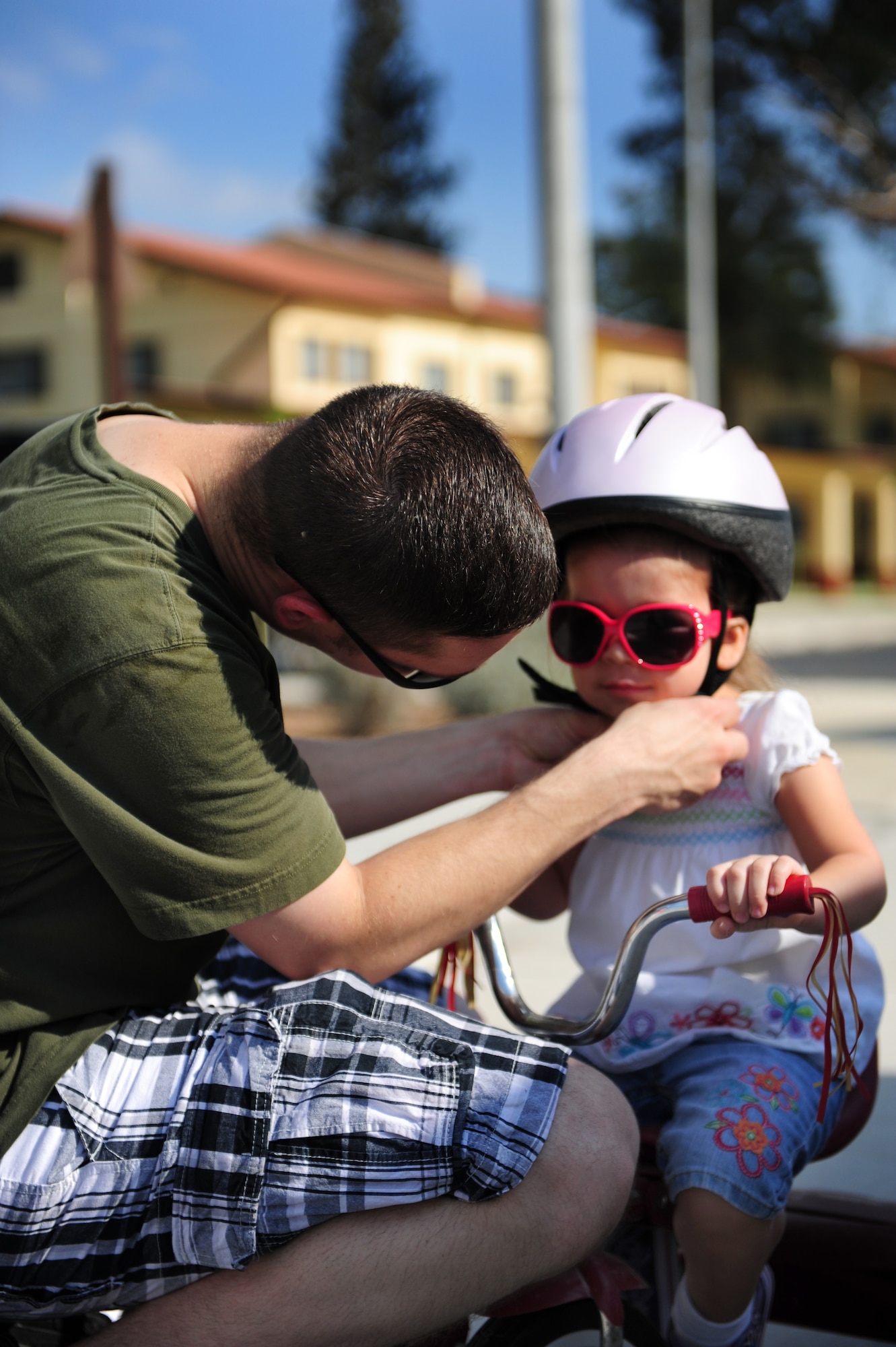Maj. Jason Redlin, 39th Air Base Wing chief of safety, fastens a helmet on his daughter during a Bicycle Safety Rodeo Aug. 20, 2011, at Incirlik Air Base, Turkey. The annual event is designed to inform riders of all ages about proper safety techniques to use while riding a bicycle. (U.S. Air Force photo by Senior Airman Anthony Sanchelli/Released) 