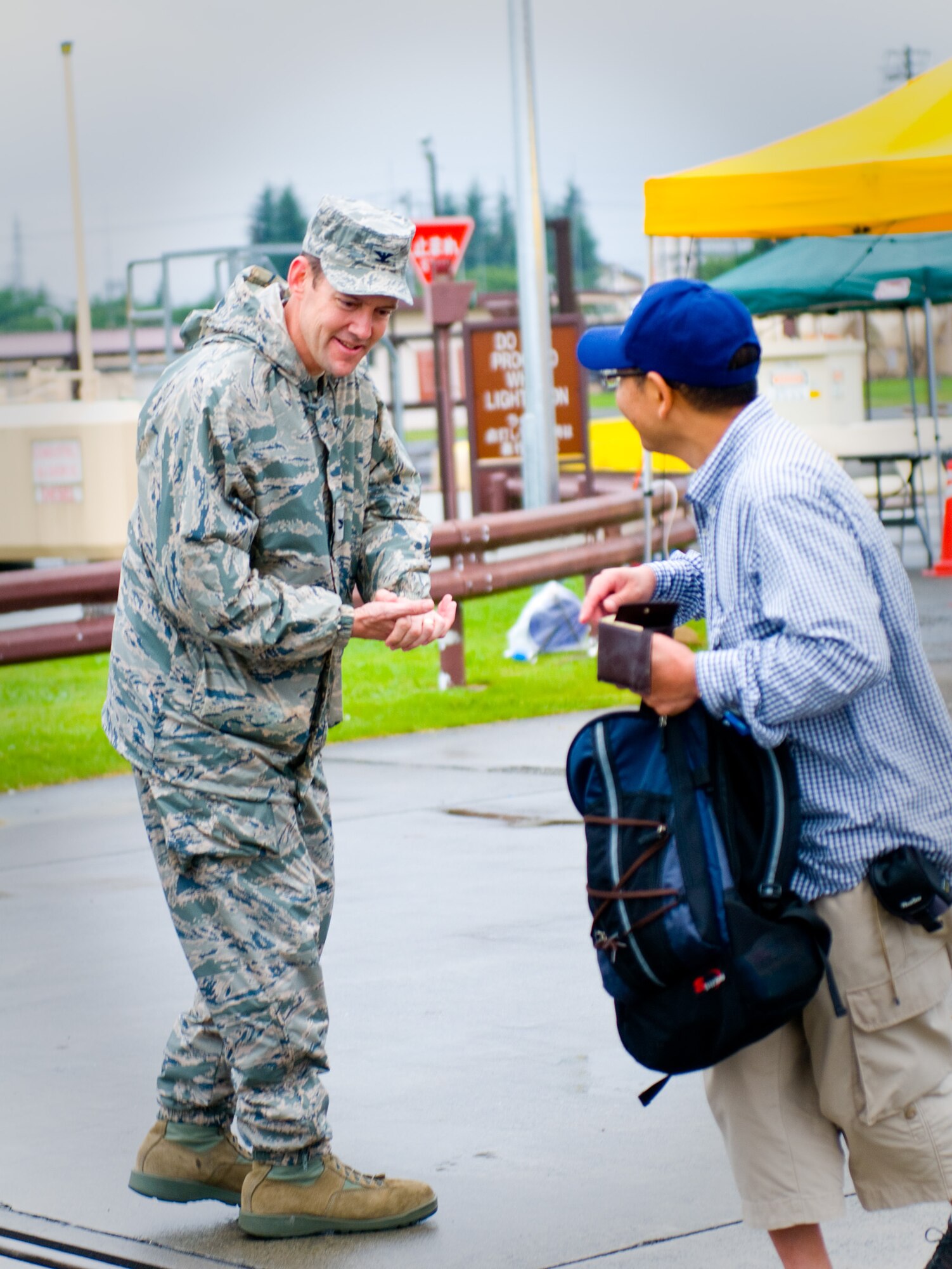 YOKOTA AIR BASE, Japan -- Col. Todd Freece, 374th Mission Support Group commander, coins the first visitor of the day to attend the Japanese-American Friendship Festival at Yokota Air Base, Japan, Aug. 21, 2011. This two-day festival is held annually as a way to strengthen ties between Yokota and the surrounding communities. (U.S. Air Force photo/Airman 1st Class Krystal M. Garrett) 
