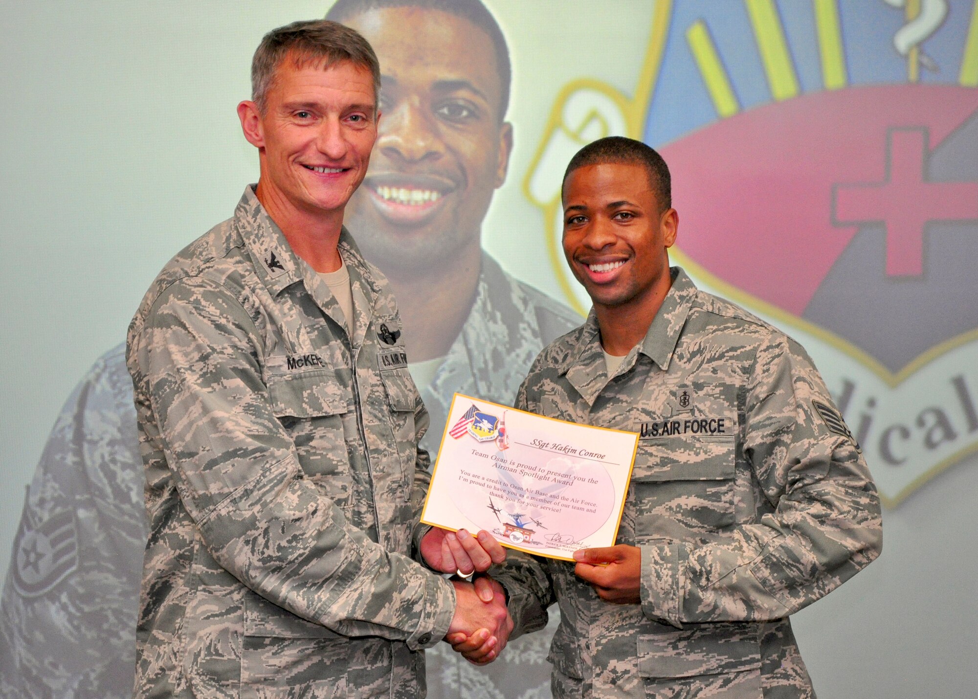Col. Patrick McKenzie, 51st Fighter Wing commander, awards Staff Sgt. Hakim Conroe, 51st Medical Support Squadron, with a certificate recognizing him as the Airman Spotlight of the week August 23, 2011. (U.S. Air Force photo/Tech. Sgt. Chad Thompson)