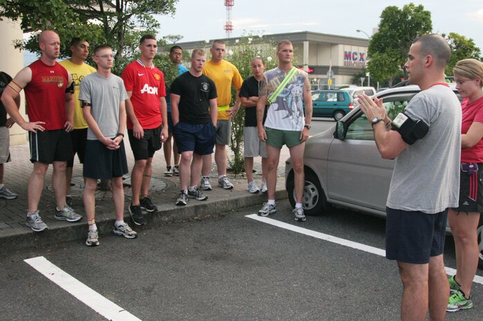 Haley Singler, Iwakuni Roadrunners’ cofounder and treasurer, and Staff Sgt. Paul S. Mancuso, Iwakuni Roadrunners’ cofounder, explain some of the club’s rules to new members outside Crossroads Mall here Aug. 24. Camaraderie and improving physical fitness are the group’s main goals.
