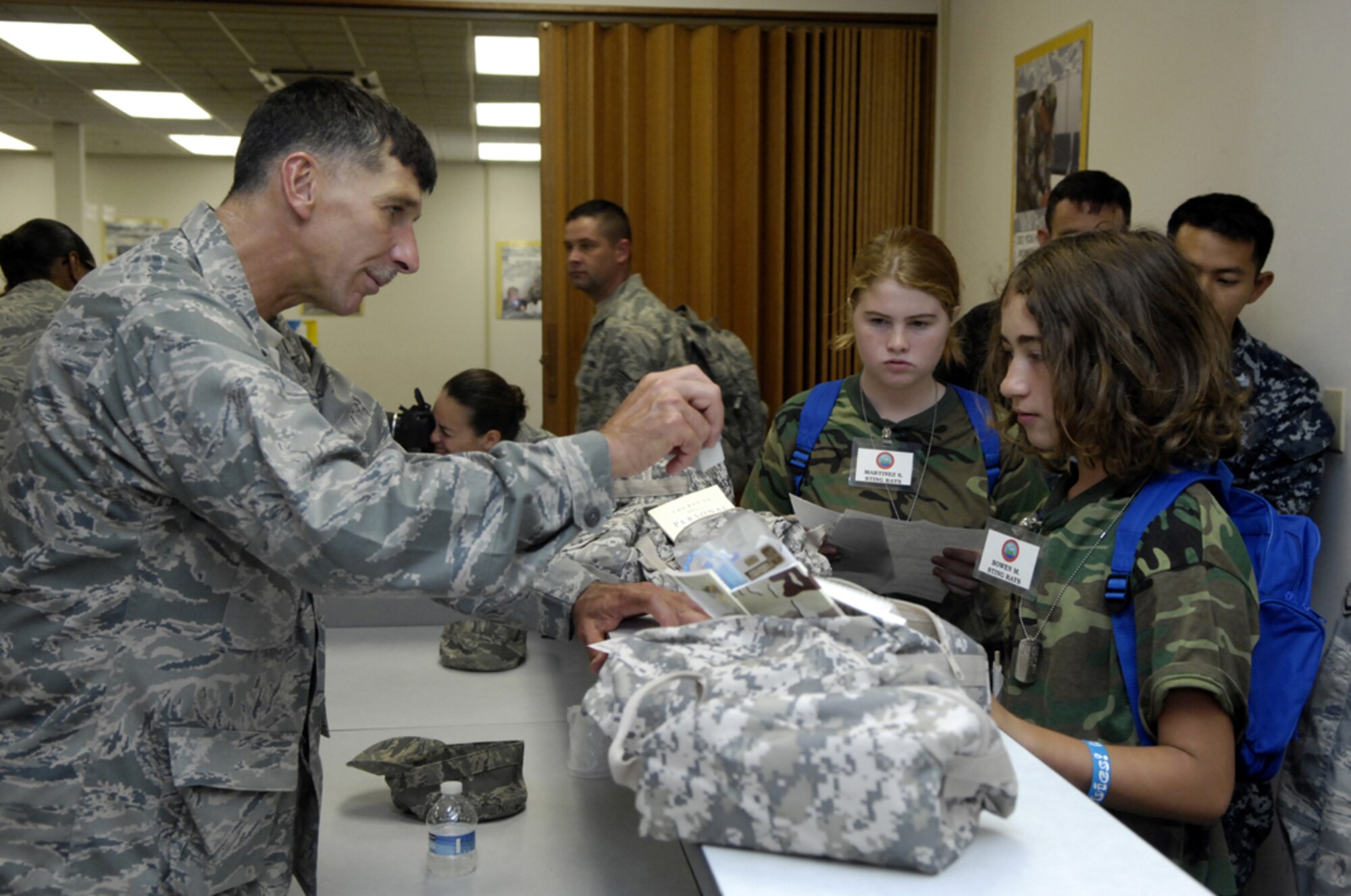 Lt. Col. Joseph Deichert, 647th Air Base Group chaplain, stamps paperwork for Mark Bowen and Sequoia Martinez in a mobility processing line during Operation Hele-On, a mock deployment for military families at Joint Base Pearl Harbor-Hickam, Hawaii, Aug 19. 155 children participated in the annual event, which included getting mobility bags and "gear" issued, getting bussed to the flight line, and a tour of the KC-135. This experience was geared to help children understand what their parents go through during a real military deployment. (U.S. Air Force photo/David D. Underwood, Jr.)
