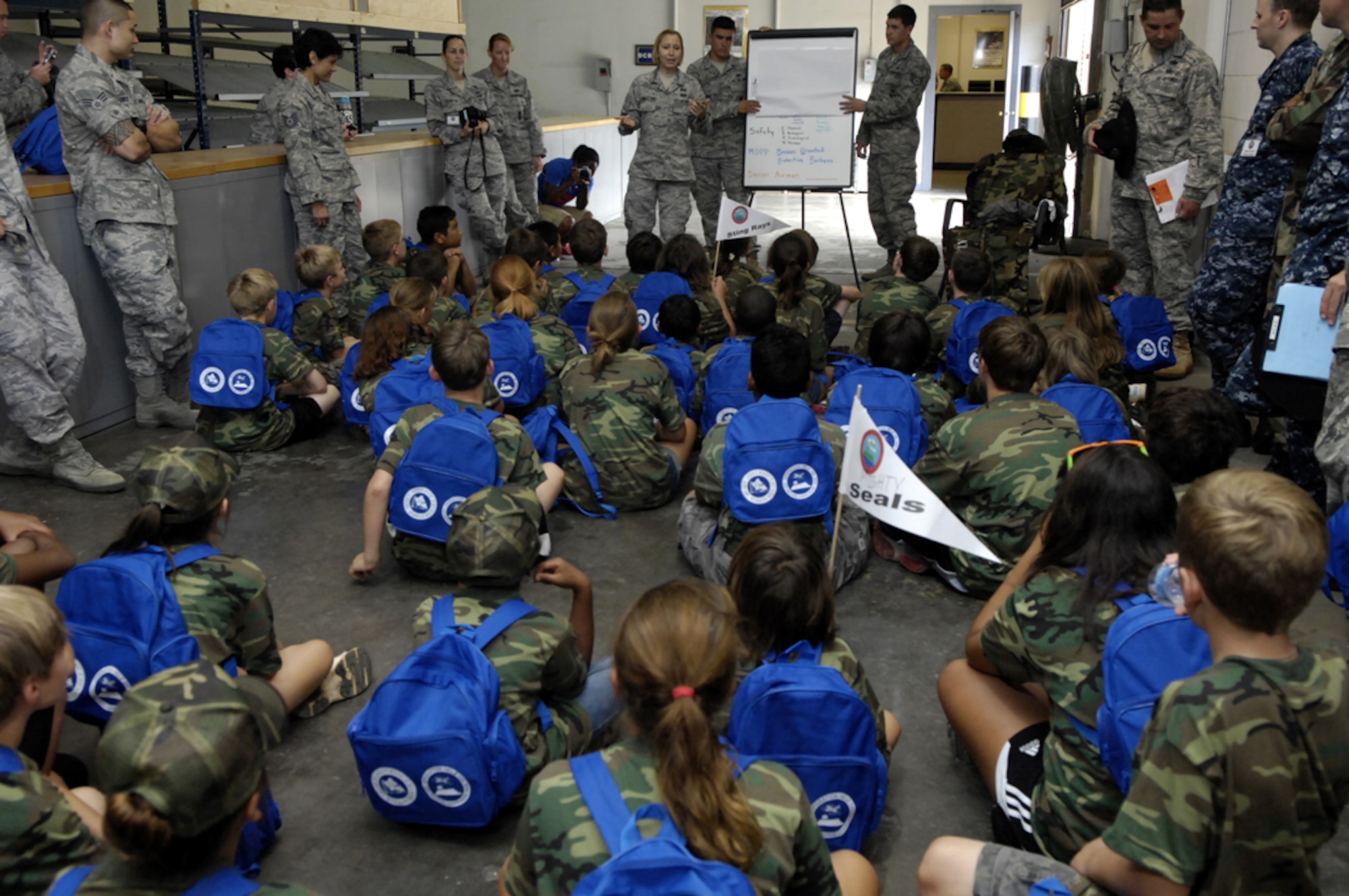 Children learn about "MOPP" (Mission Oriented Protective Posture) gear as part of their "mobility processing" during Operation Hele-On, a mock deployment for military families at Joint Base Pearl Harbor-Hickam, Hawaii, Aug 19. 155 children participated in the annual event, which included getting mobility bags and "gear" issued, getting bussed to the flight line, and a tour of the KC-135. This experience was geared to help children understand what their parents go through during a real military deployment. (U.S. Air Force photo/David D. Underwood, Jr.)
